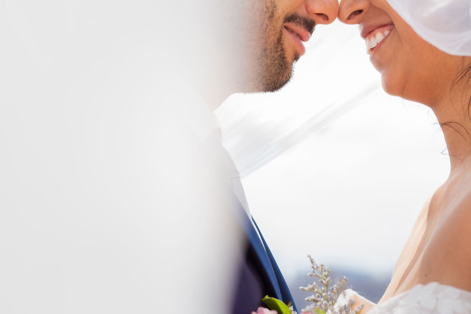 A close-up wedding scene with white wedding dress fabric and small blue and green floral details.