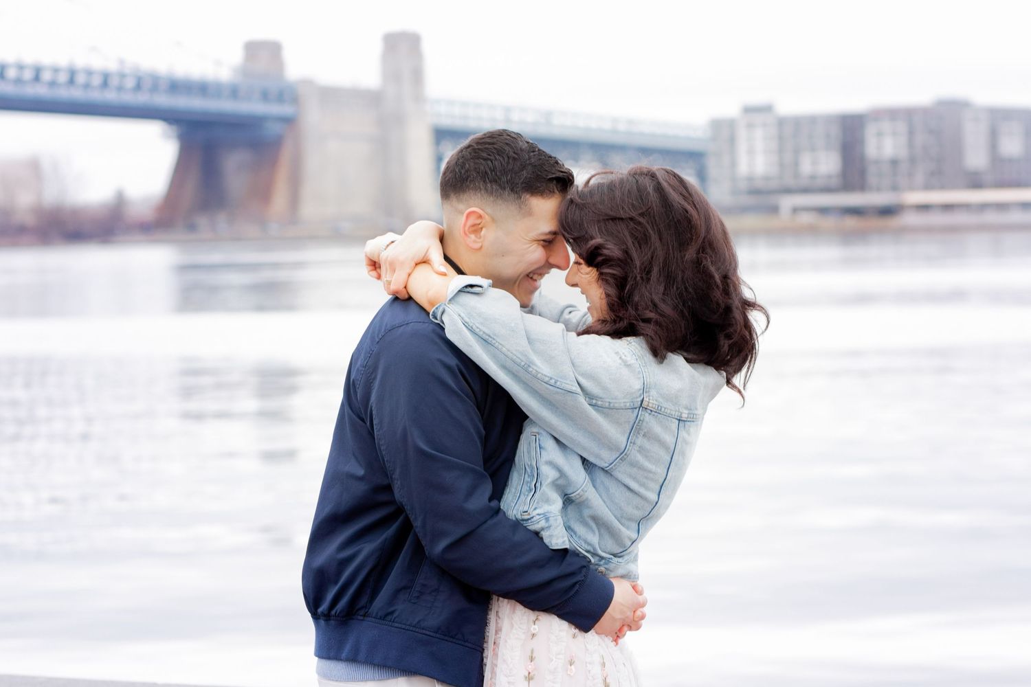 Romantic couple embraces and kisses by the waterfront on an overcast winter day.