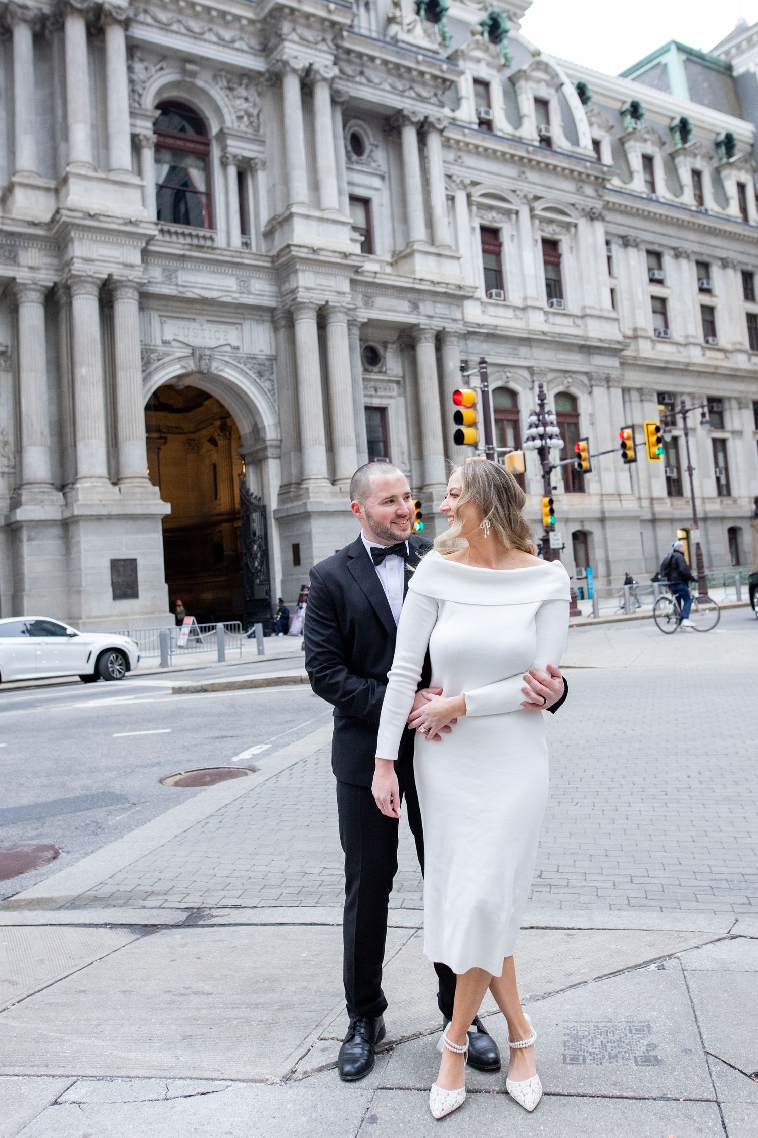 A couple dances gracefully on a city sidewalk in front of a grand historic building with ornate architecture and columns.