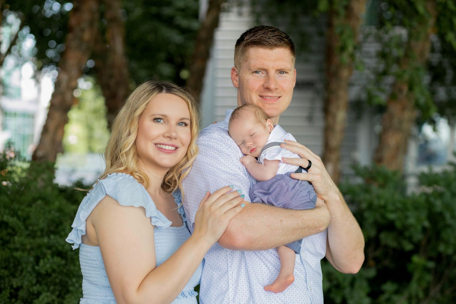 A loving family poses together outdoors in matching blue and white outfits on a sunny day.