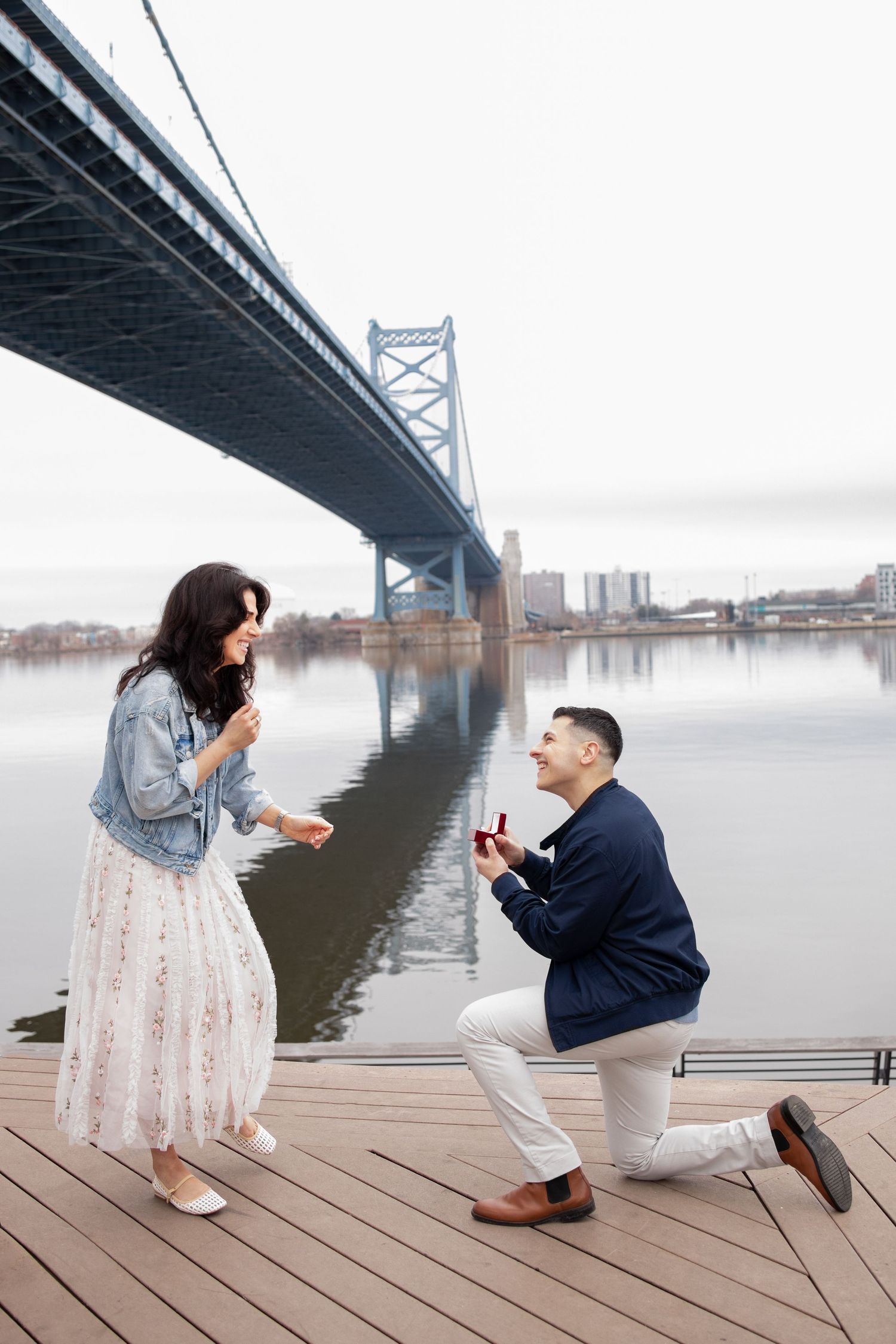 Proposal photoshoot sequence under the Benjamin Franklin Bridge in Philadelphia during a misty day along the waterfront.