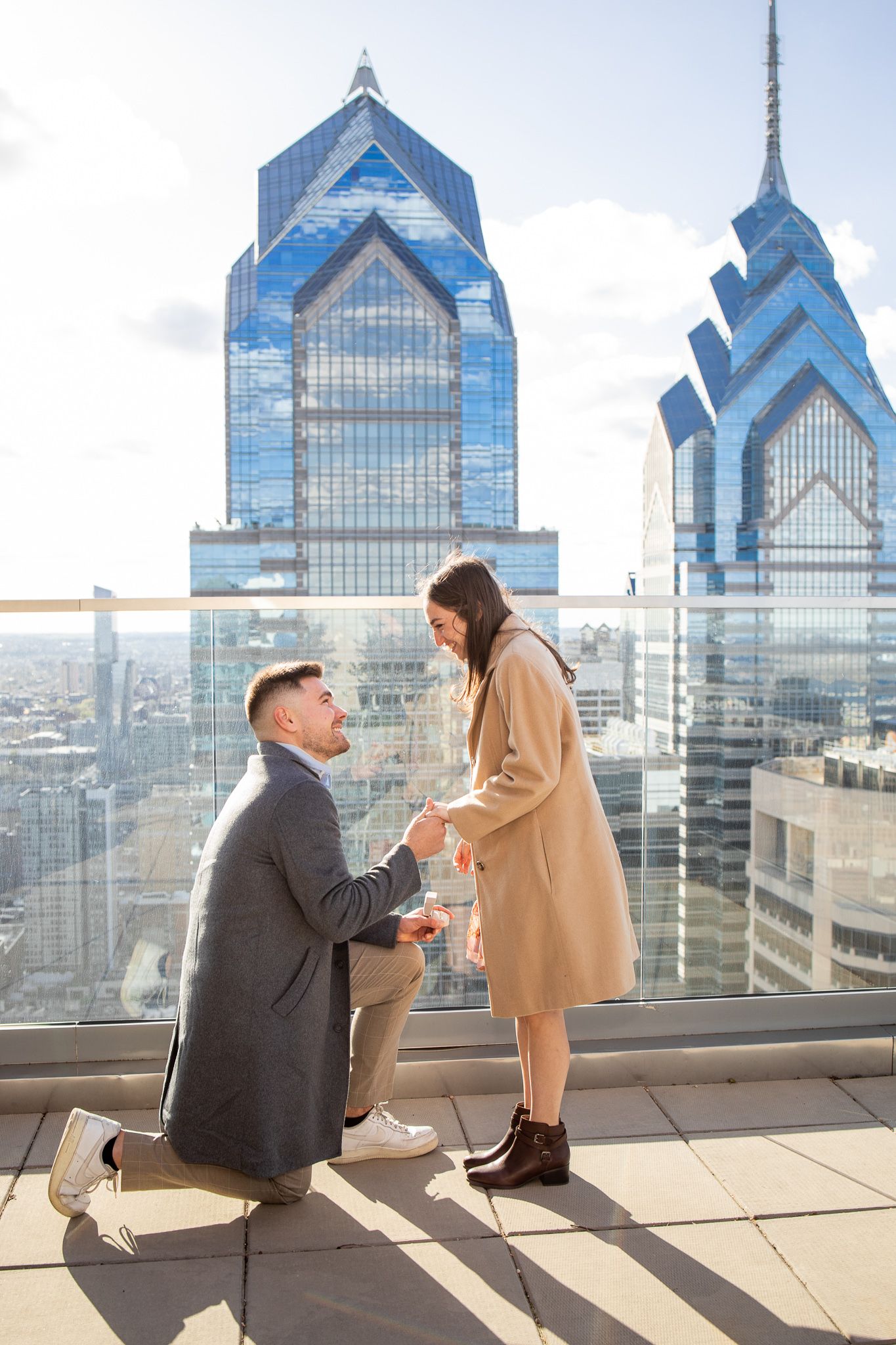 A romantic rooftop proposal scene against Philadelphia's iconic skyline with Liberty Place towers in the background.