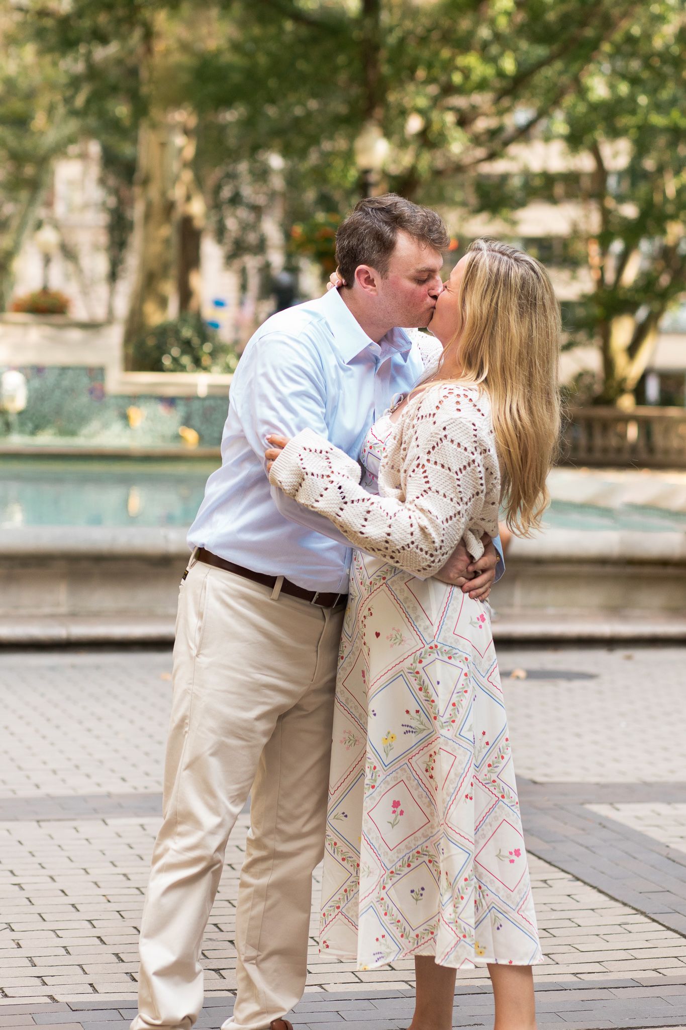 A romantic couple shares a tender moment while embracing near a fountain.