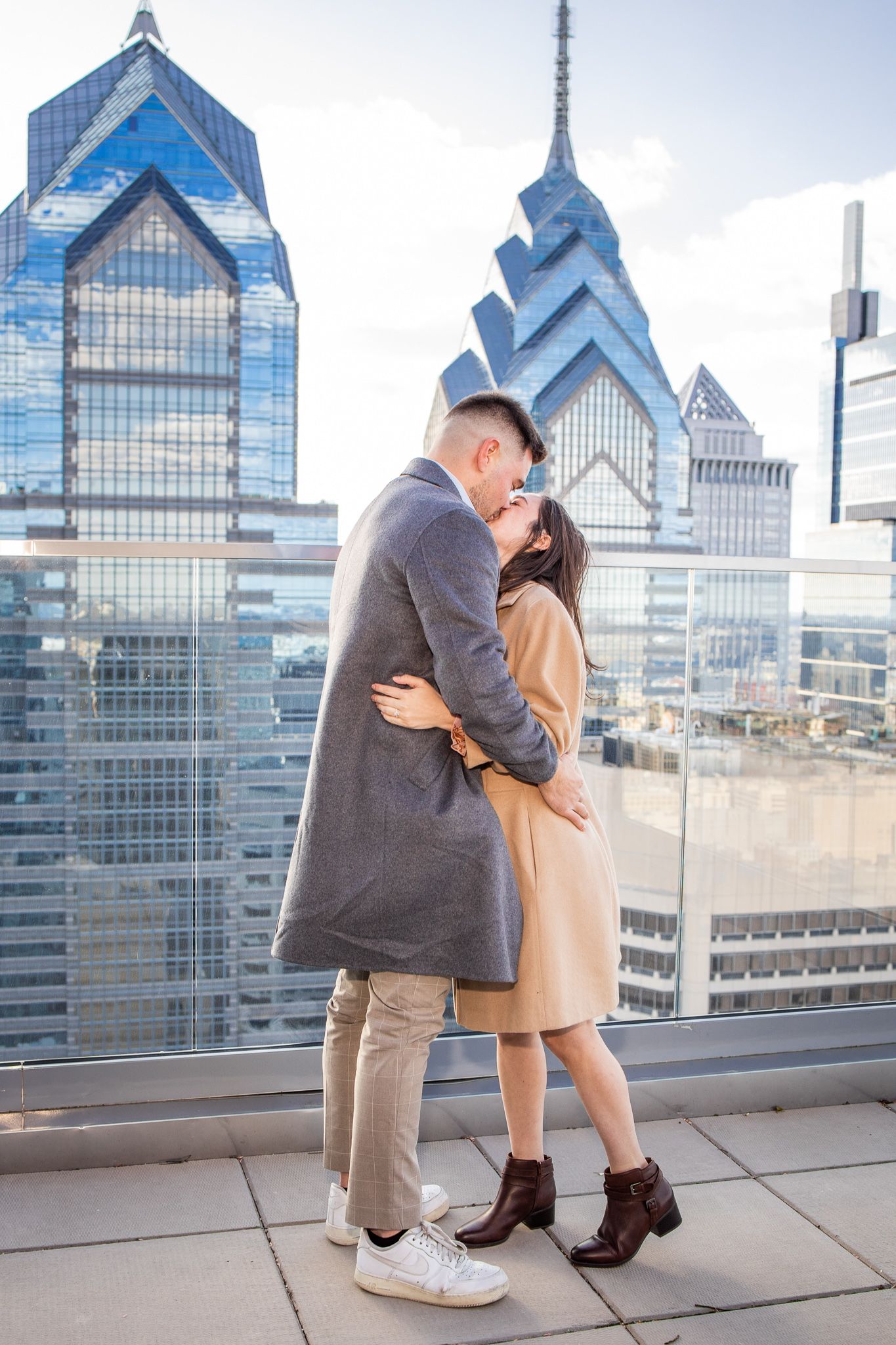 A romantic proposal sequence unfolds on a Philadelphia skyscraper observation deck with the city skyline as backdrop.