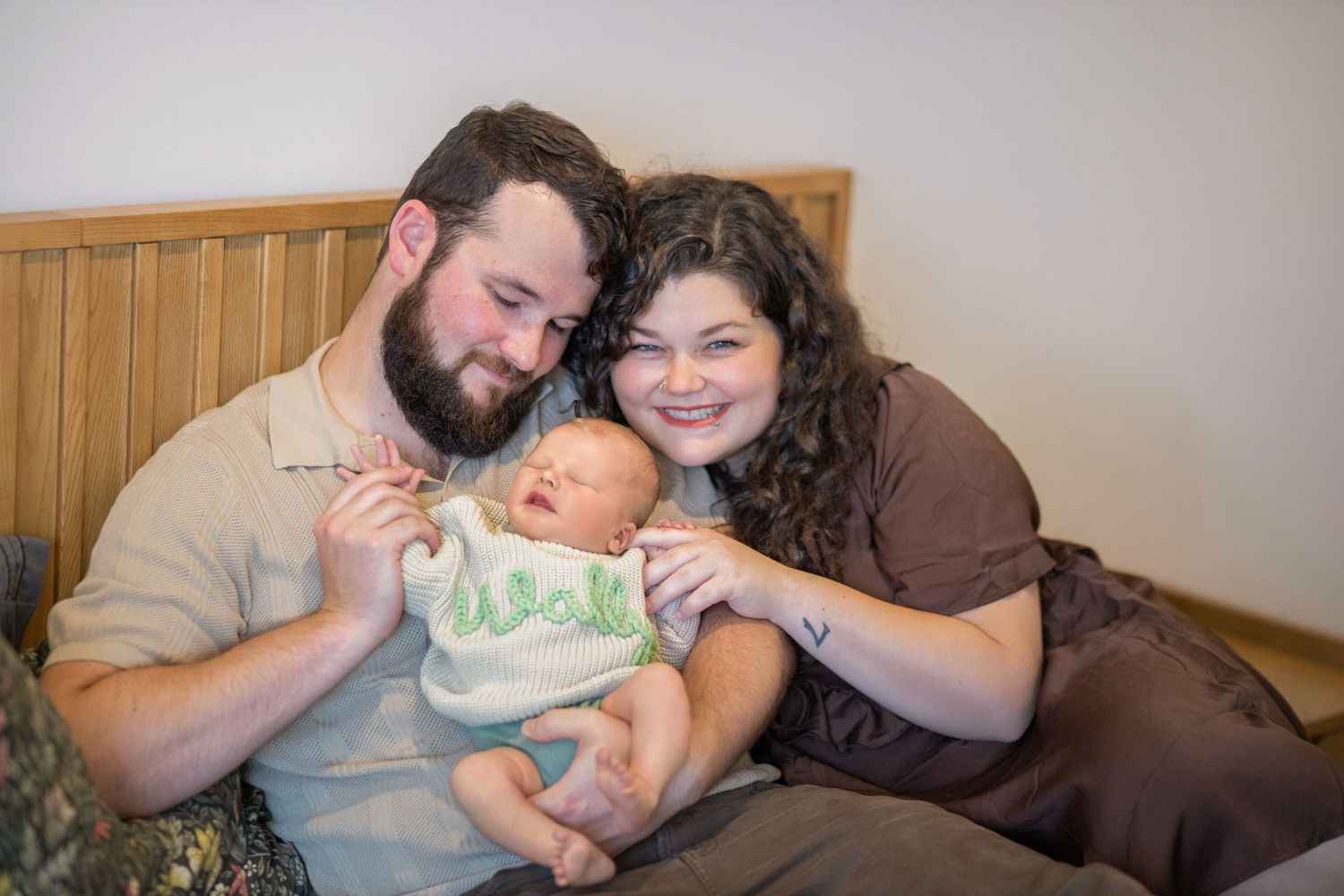 A group of people sit together on a couch sharing tender family moments with a small baby.