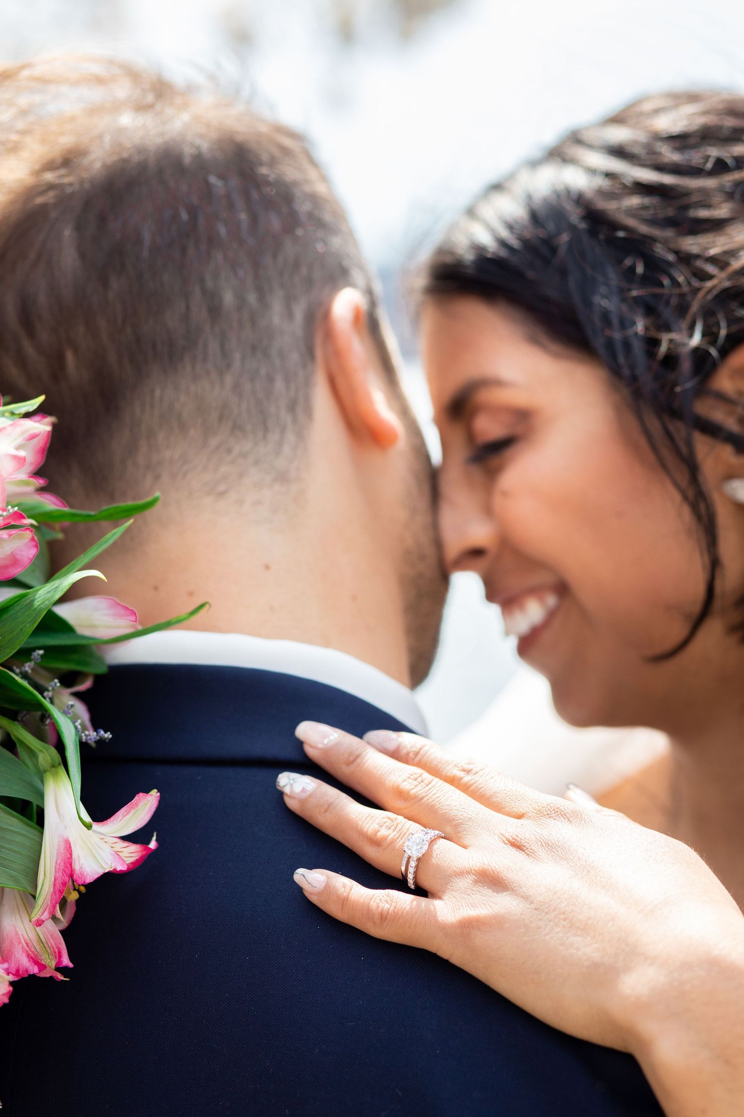 Close-up series of romantic wedding couple embracing with pink flowers visible in a tender moment.