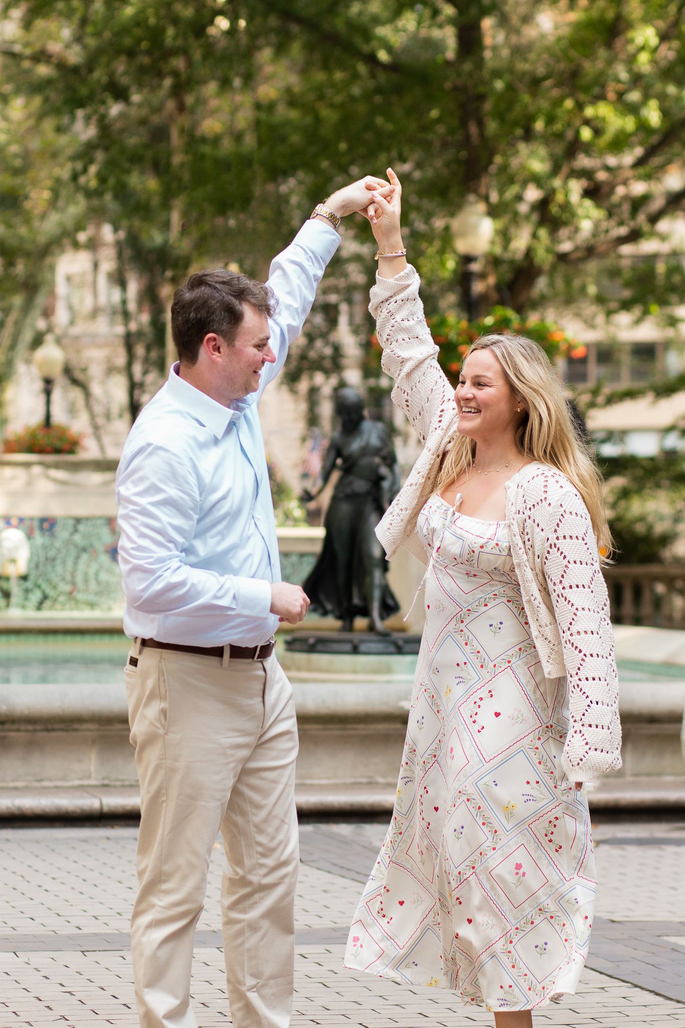 A couple dances joyfully together in an outdoor setting wearing coordinated white and beige outfits.