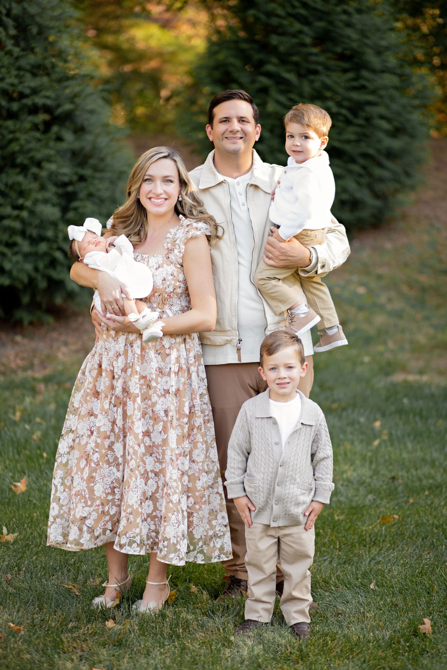 Family wearing coordinated cream and floral outfits poses outdoors in a series of candid garden portraits.