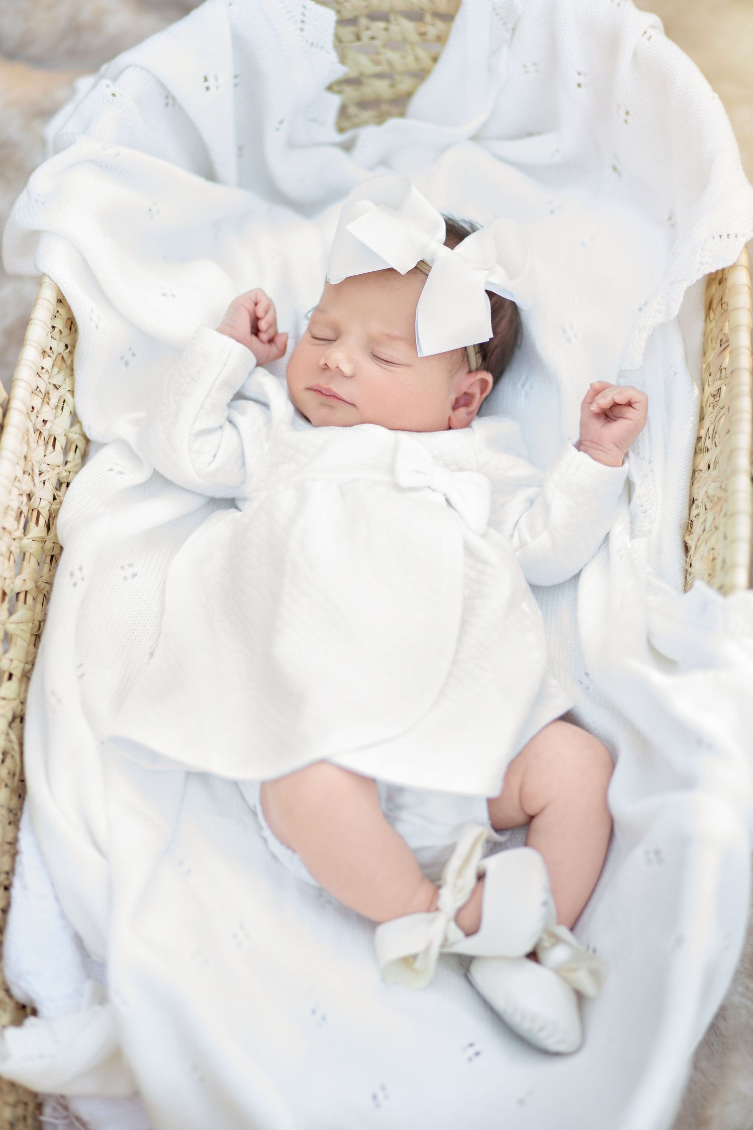 Sleeping newborn baby wrapped in soft white blankets and swaddle cloths nestled on textured backdrop.