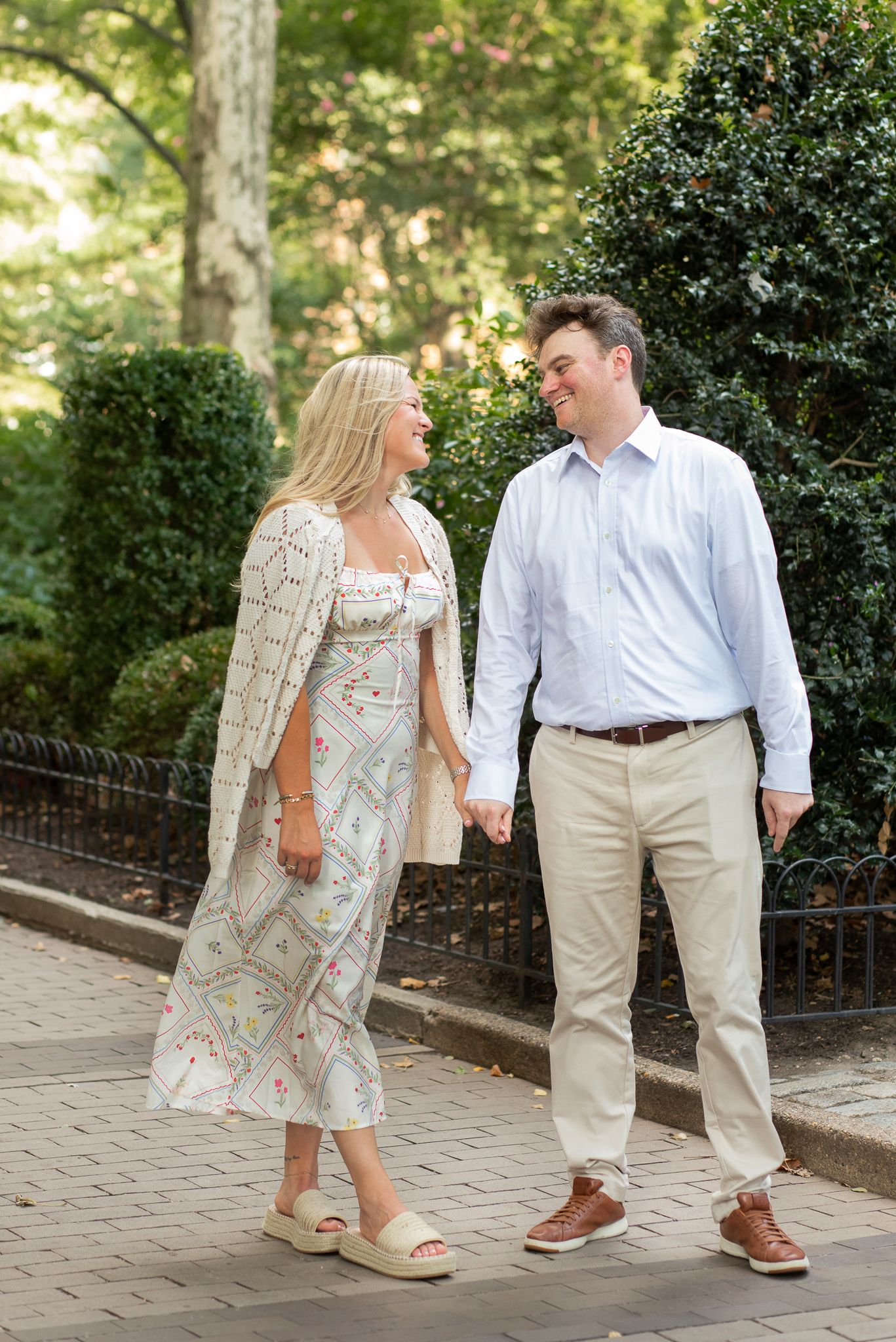 A couple takes a romantic stroll along a garden path, wearing coordinated spring outfits.