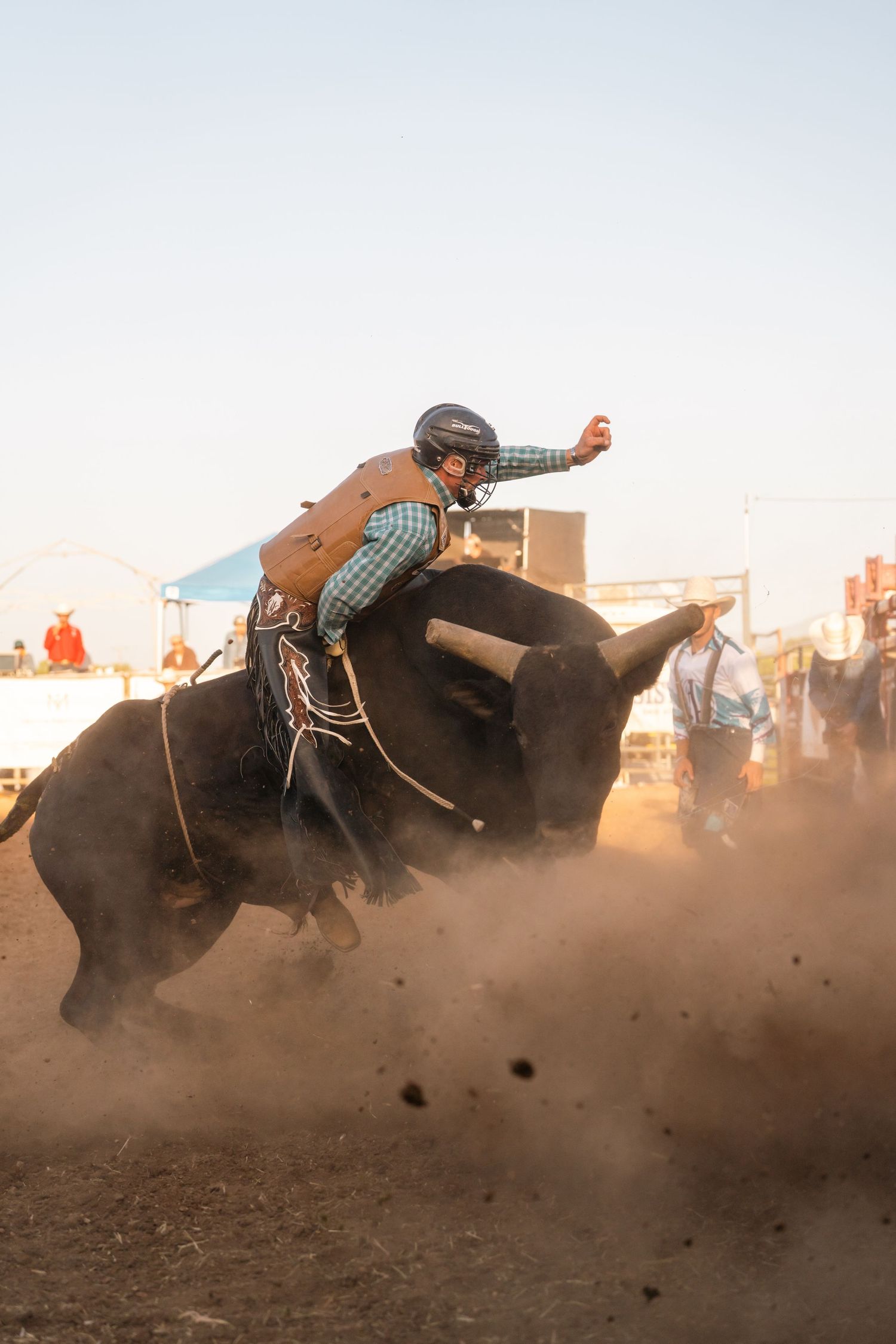 Action sequence of bull rider being thrown from bucking bull in dusty arena.