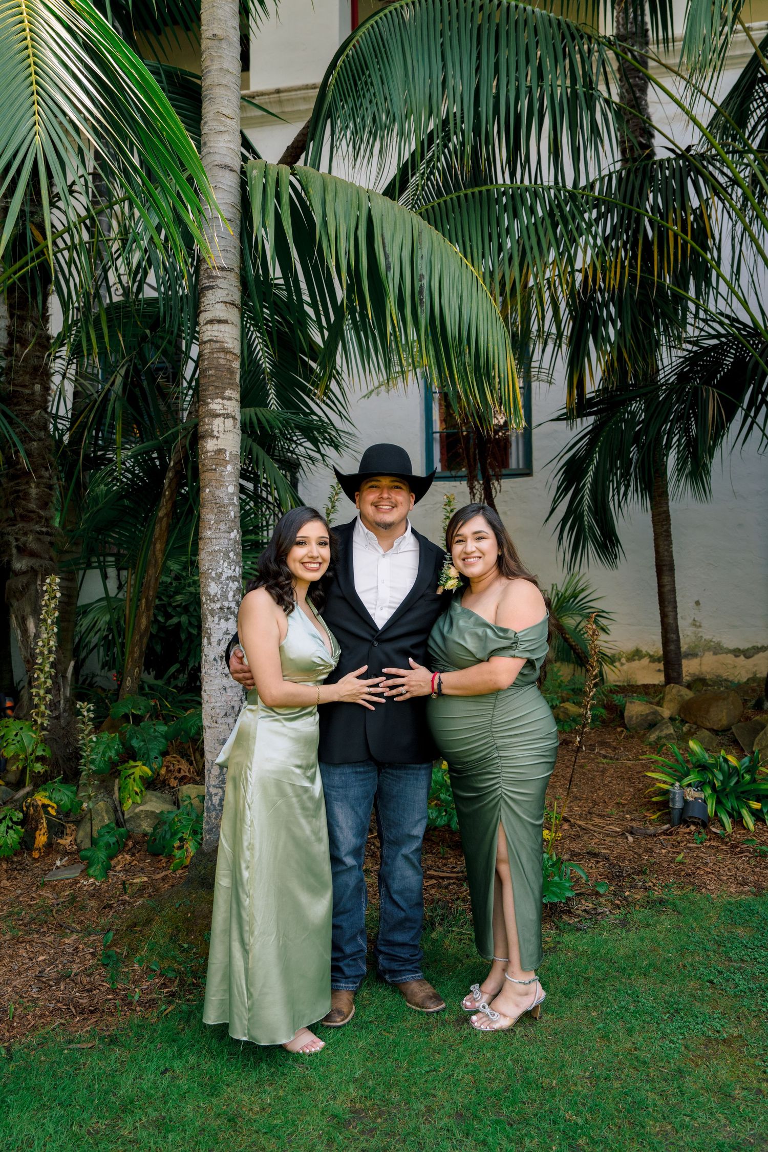 Wedding party members embrace and pose together in a lush garden setting.