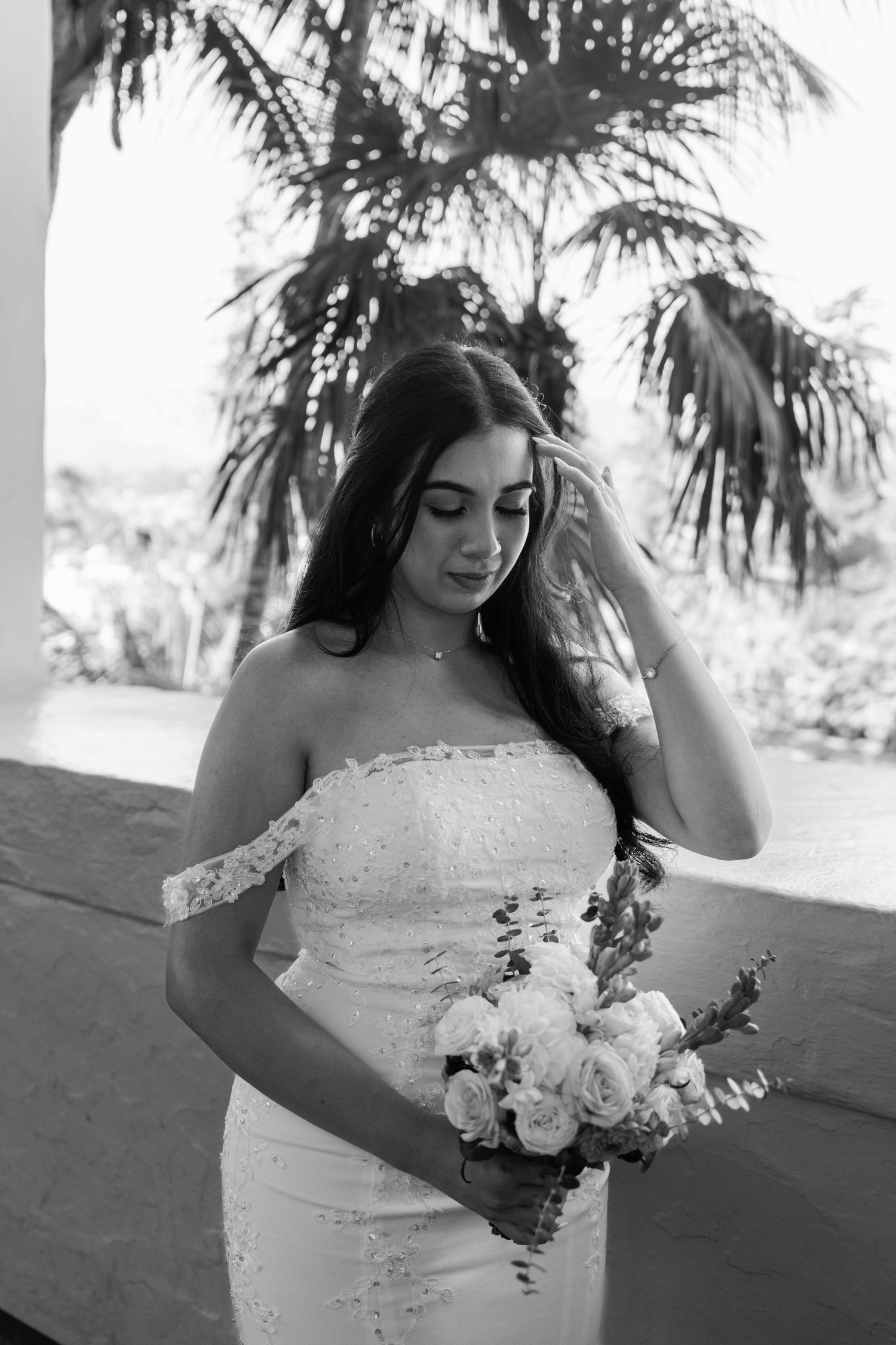 Bride holding a white and pink floral bouquet in natural outdoor lighting.