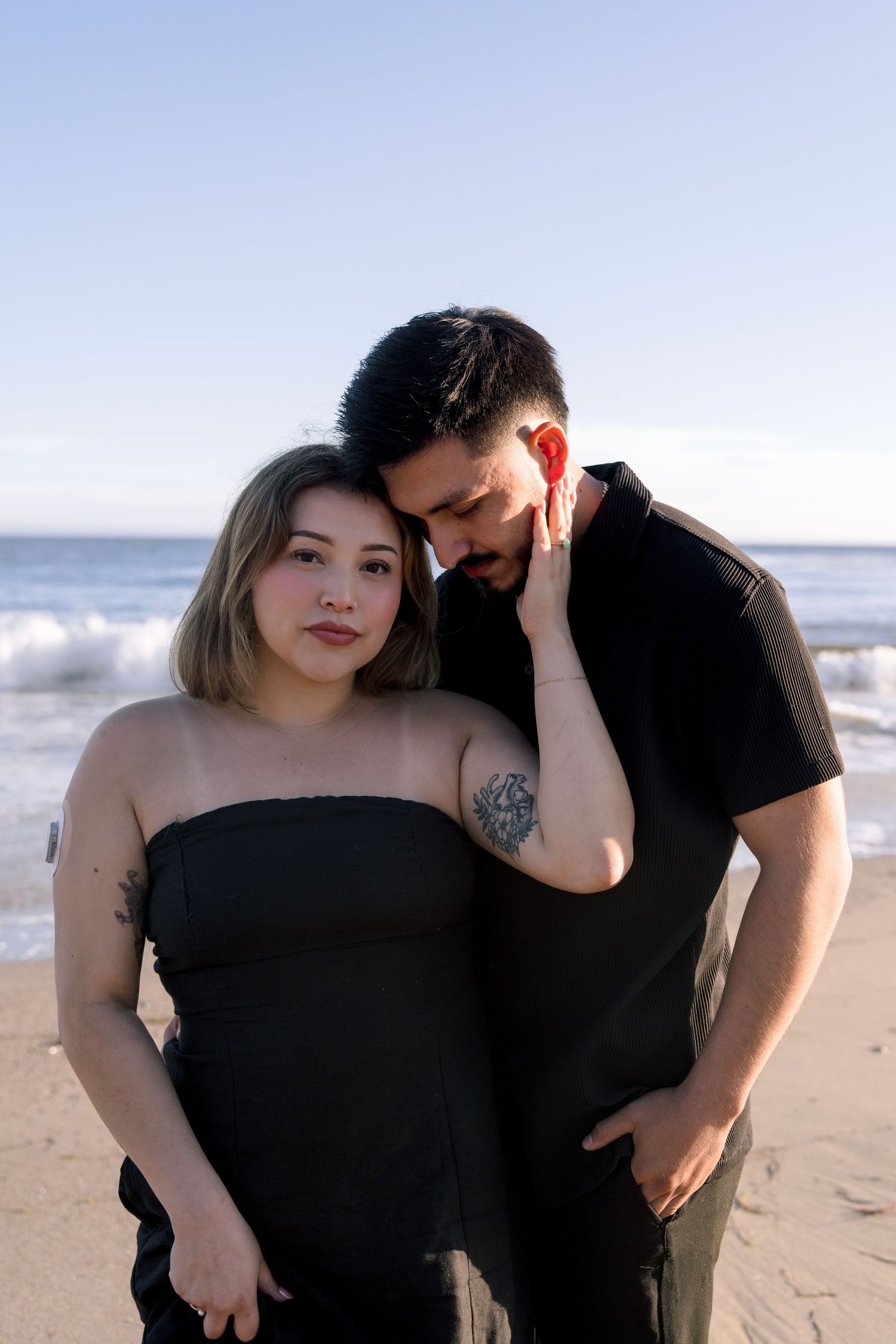 Romantic couple's portrait session on a sandy beach at sunset.