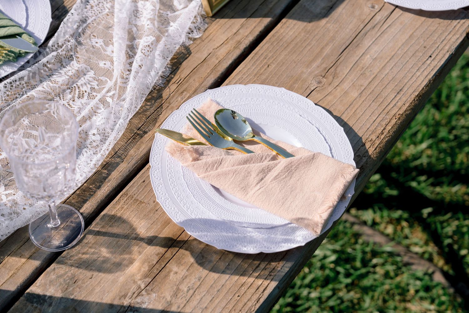 Empty wine glasses and place settings on a rustic wooden table with lace details.