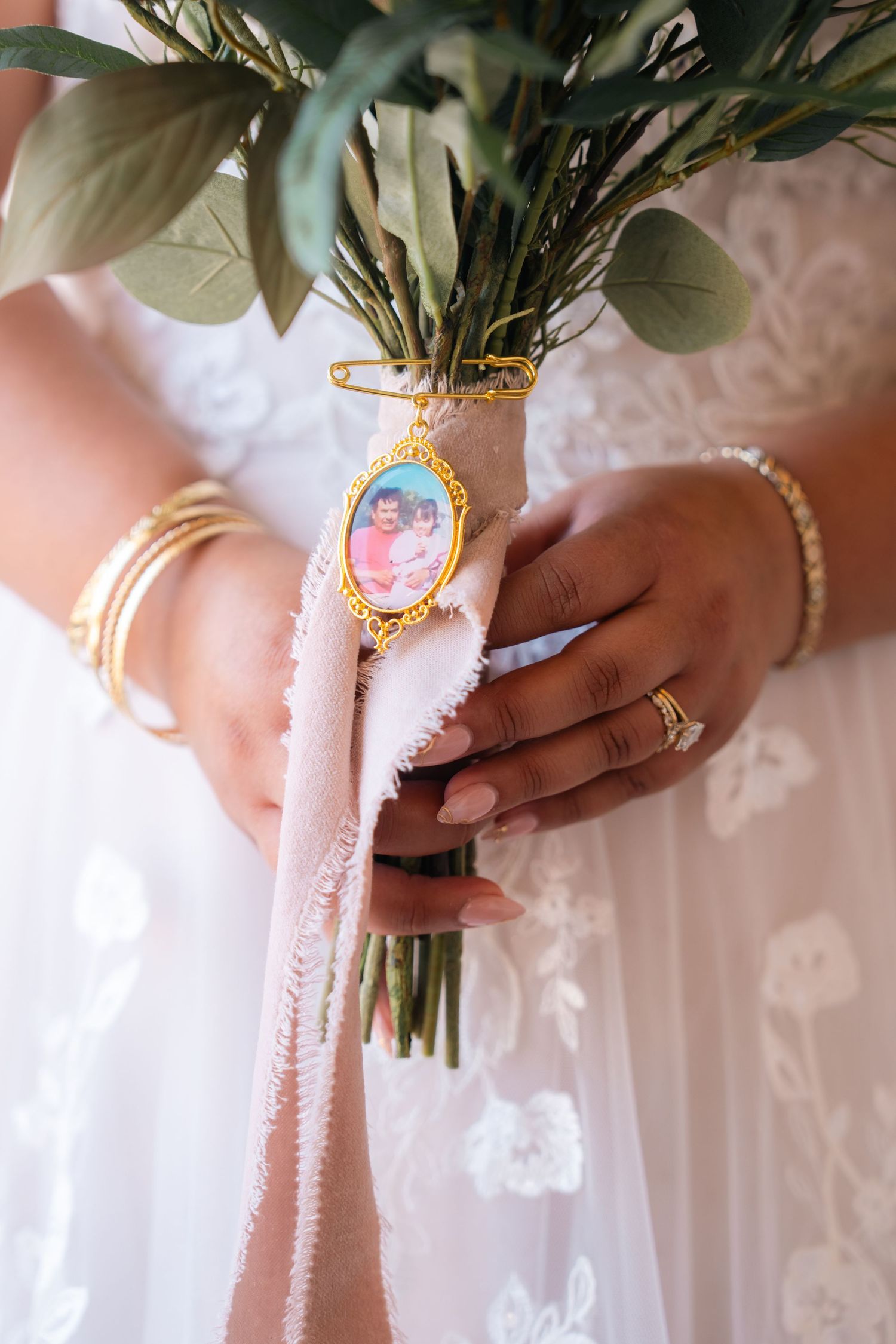 Wedding bouquet wrapped in pink ribbon with a decorative golden brooch.