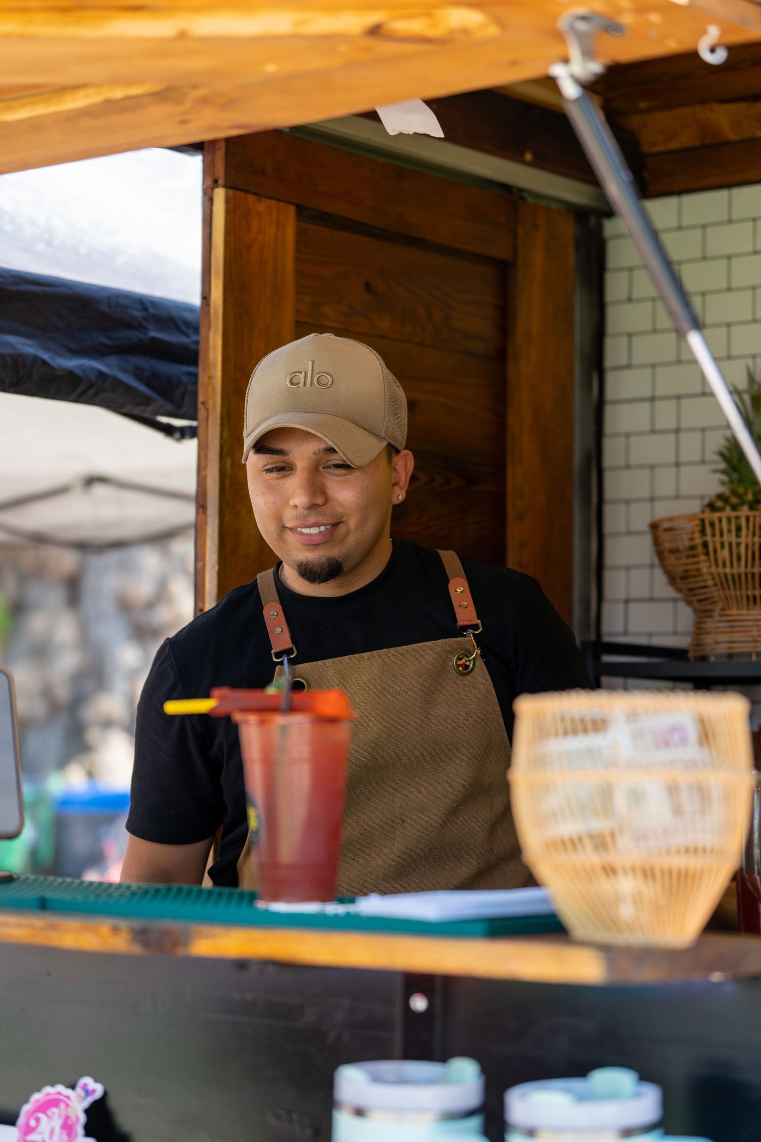 Food vendor smiling while working at outdoor market stall.