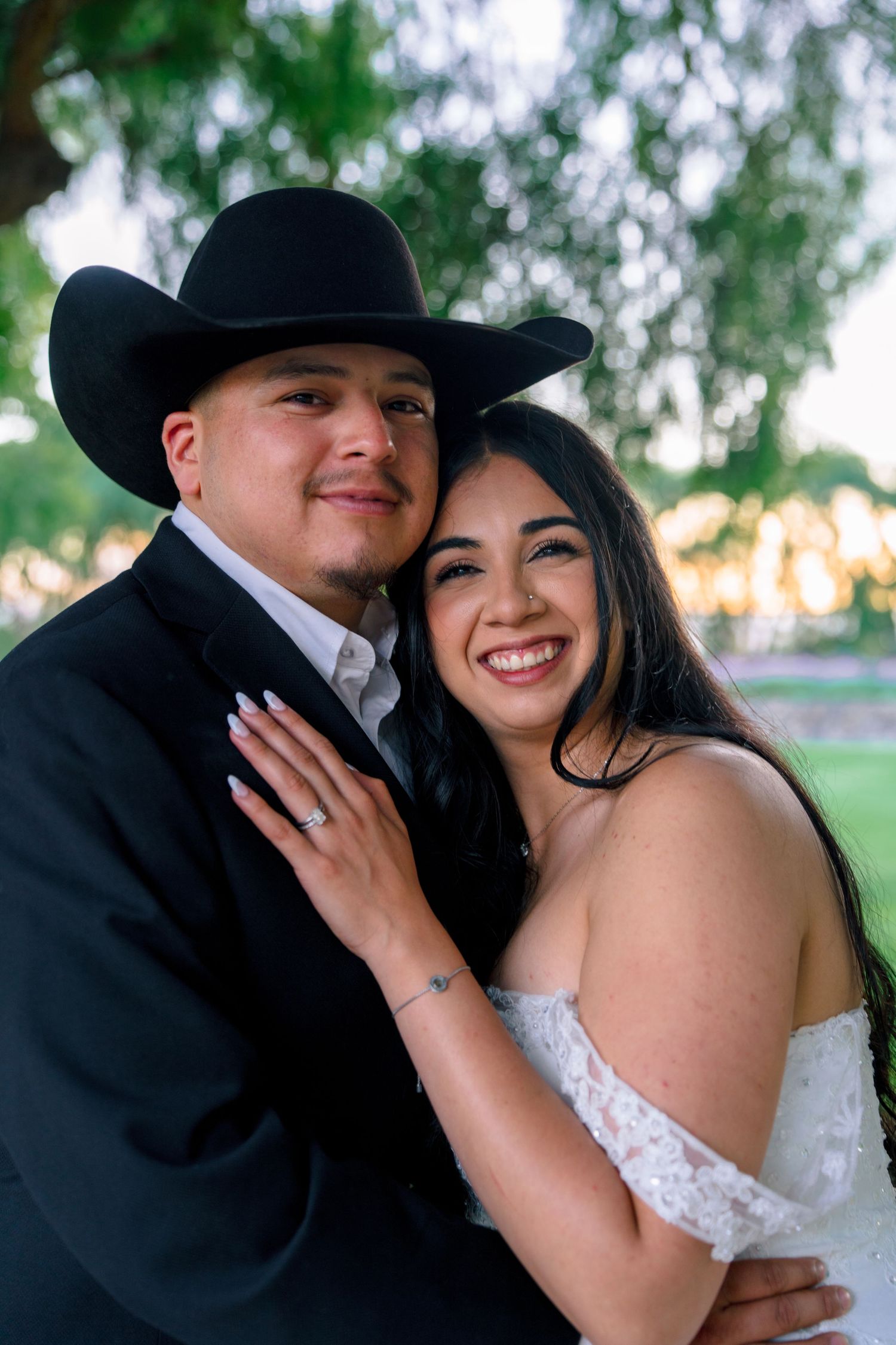 A couple in western wedding attire share an intimate moment outdoors.