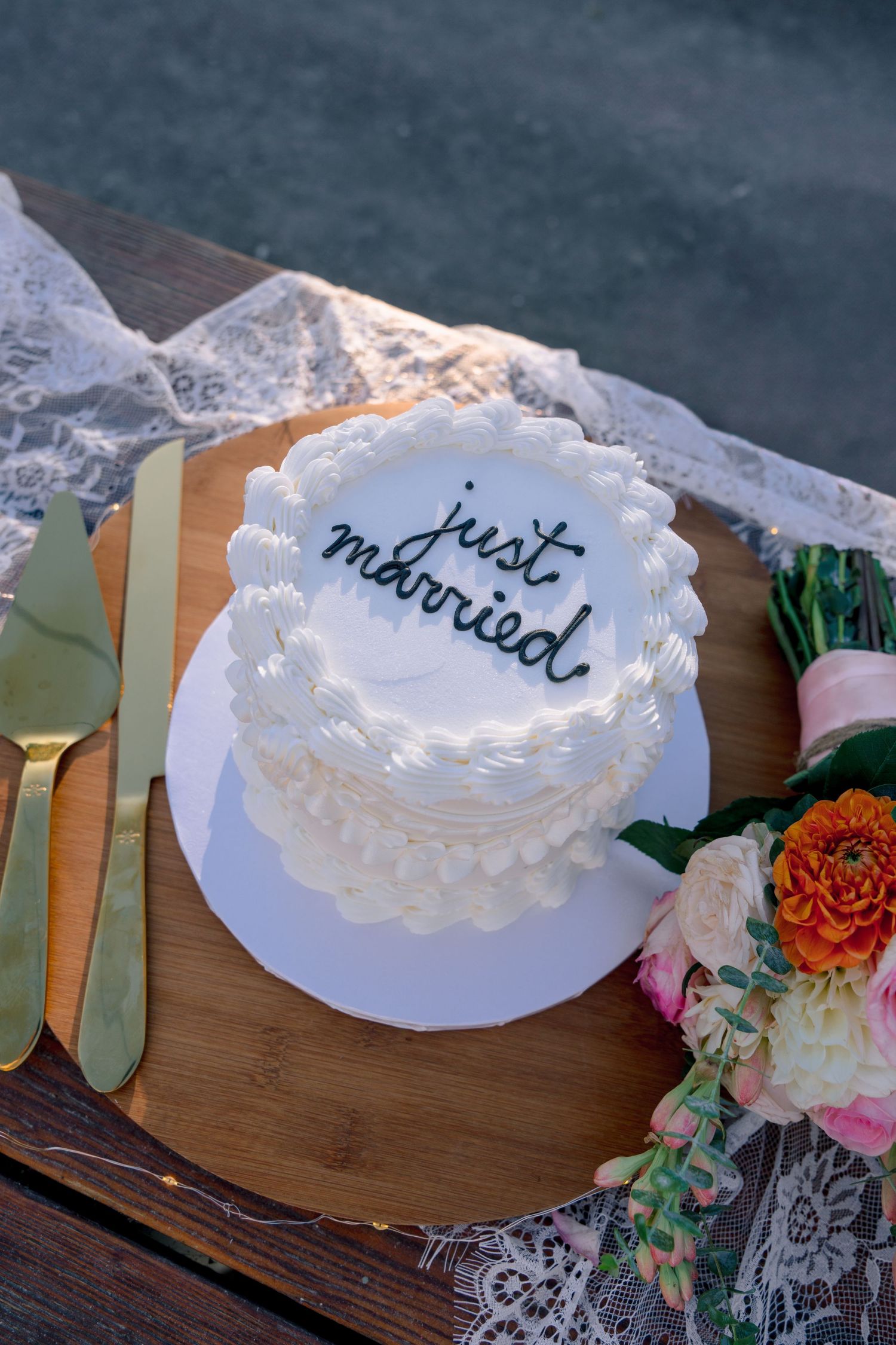 White wedding cake decorations with text displayed on wooden surfaces with floral accents.