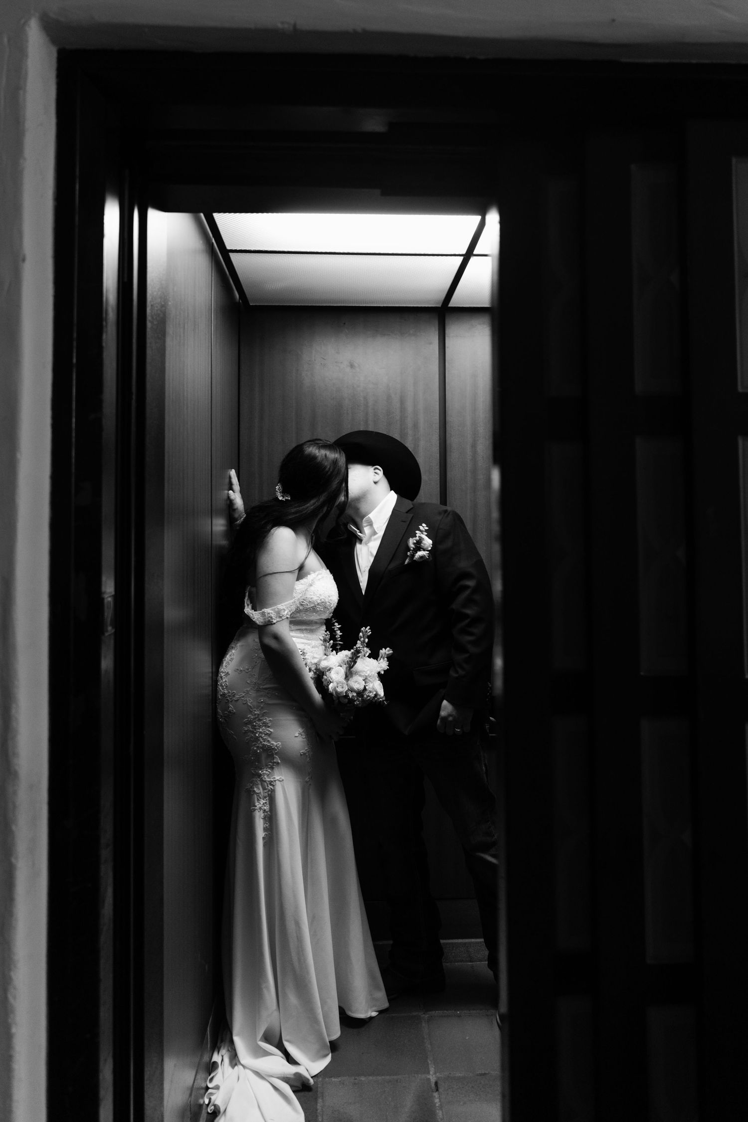 Artistic black and white wedding photo showing silhouettes in a hallway.