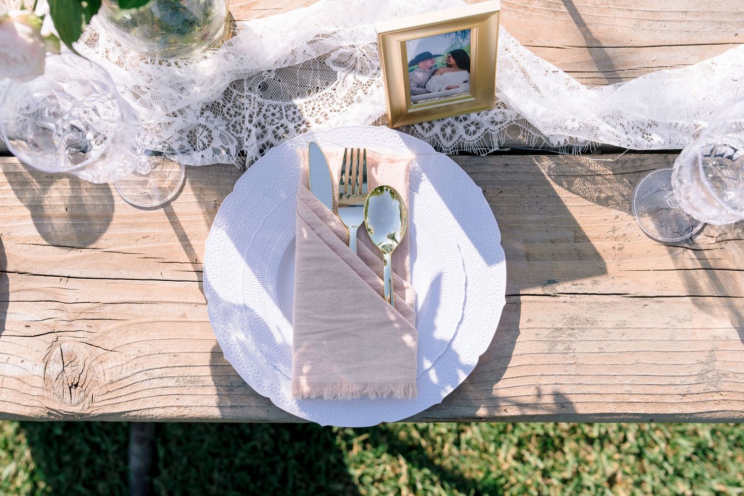 Table settings with white plates and lace details arranged on rustic wooden tables.