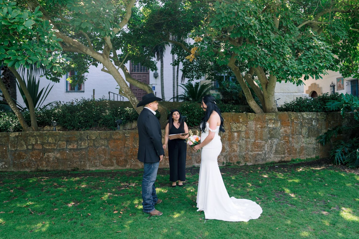 Wedding photography session taking place in green garden with stone wall.
