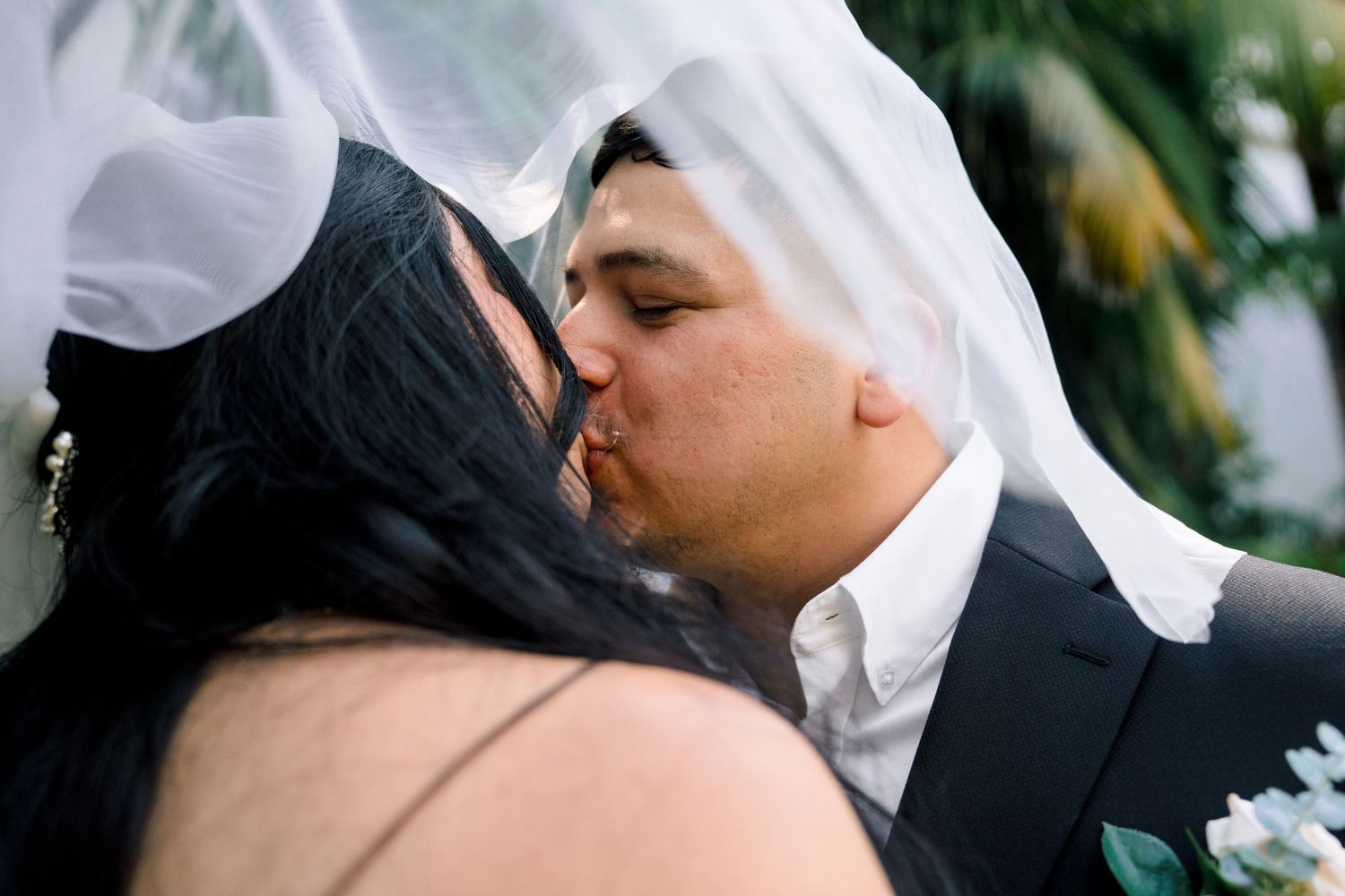 Romantic wedding moment captured through delicate white veil fabric.