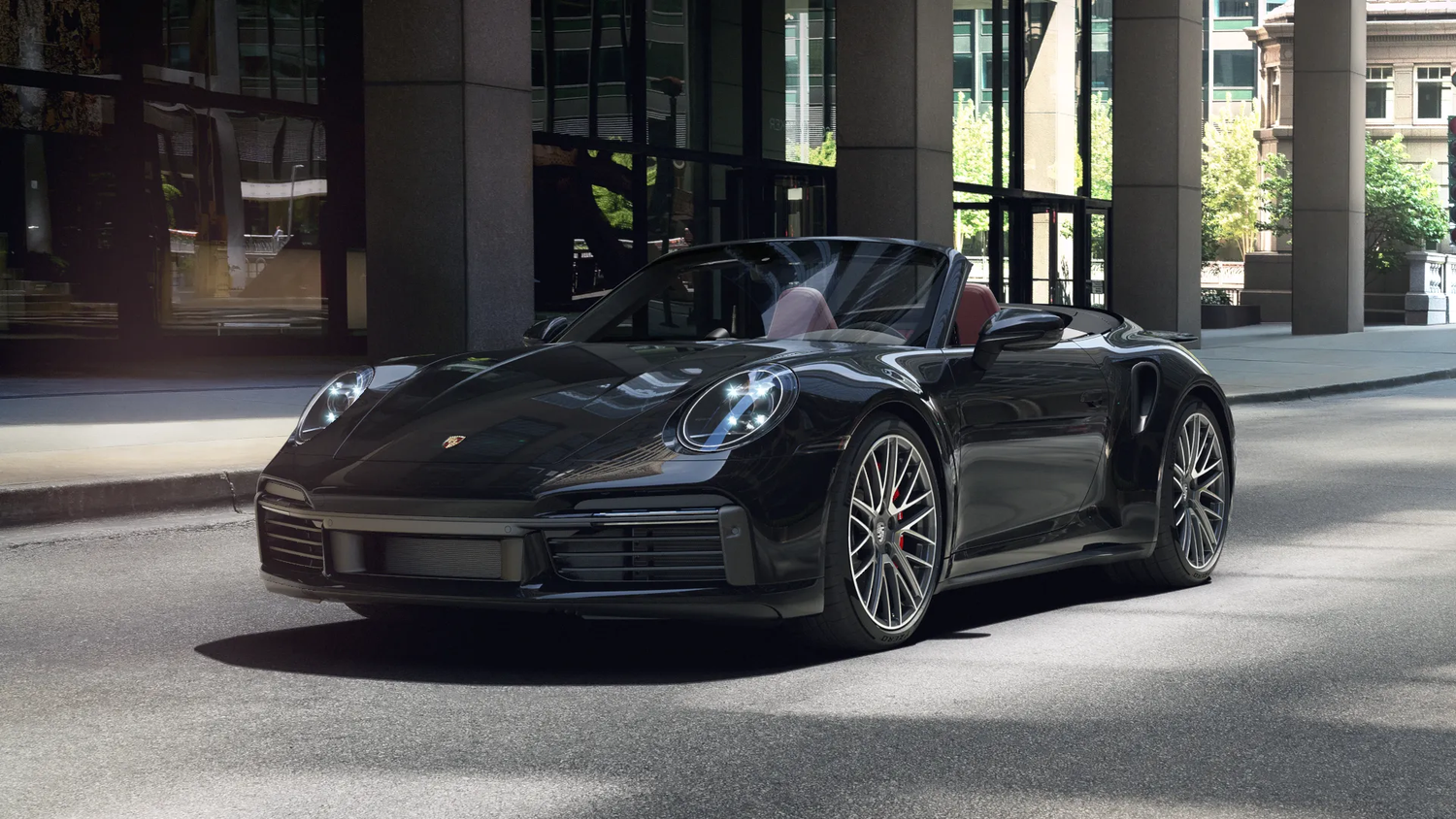 Sleek black Porsche 911 Turbo convertible lined up in a covered parking garage, showing their dramatic silhouettes and designs.