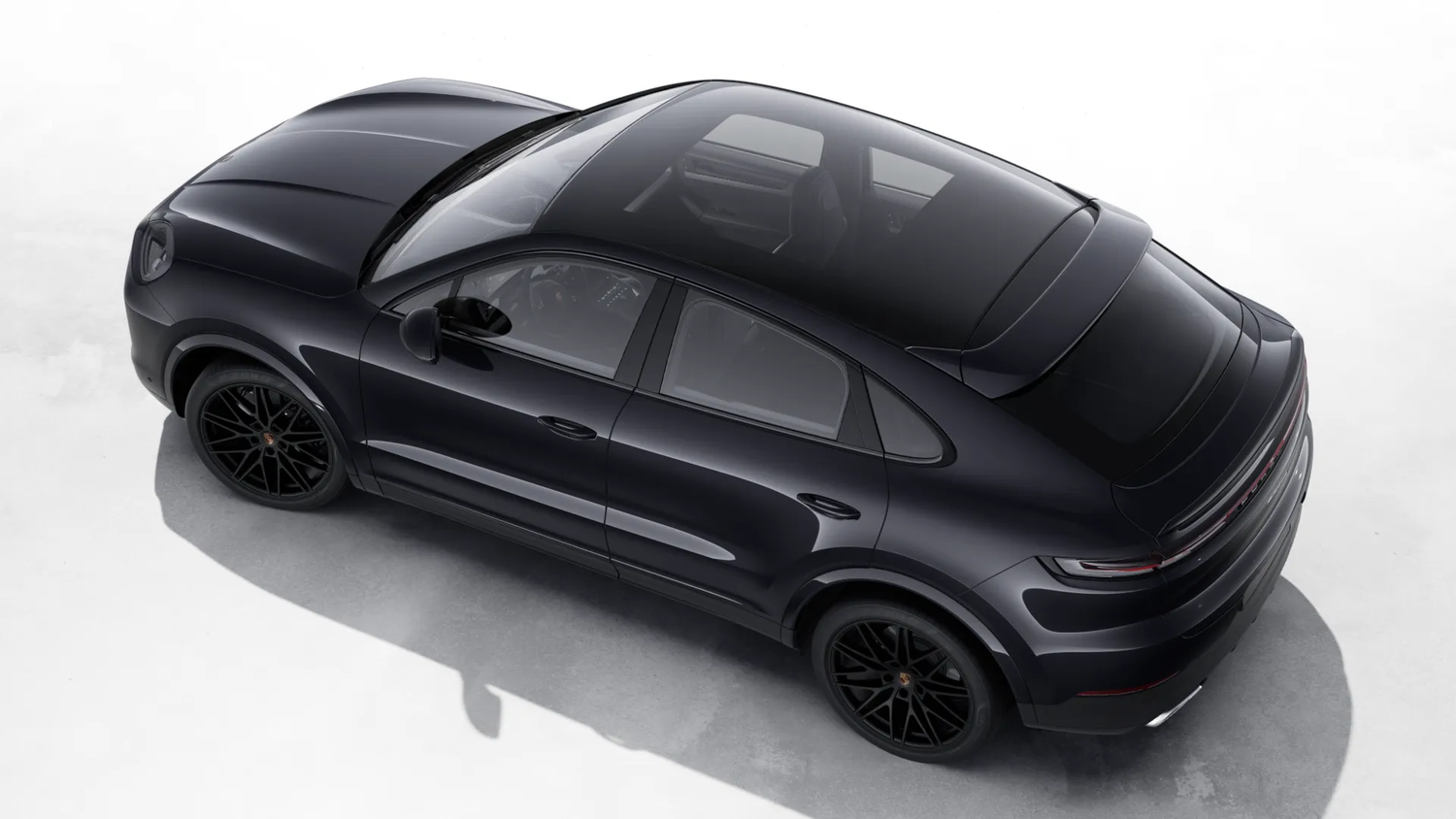 Sleek black Porsche Cayenne Coupe SUV viewed from above, showing its sporty silhouette and dark alloy wheels.