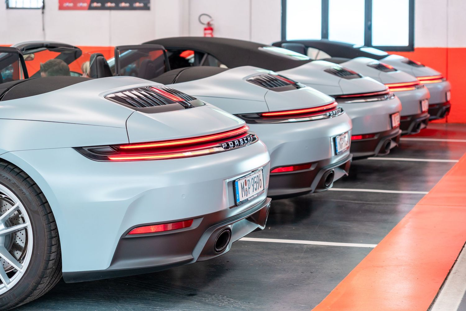 Multiple Porsche 911 GT3 sports cars in white and silver parked in formation at a showroom or dealership.