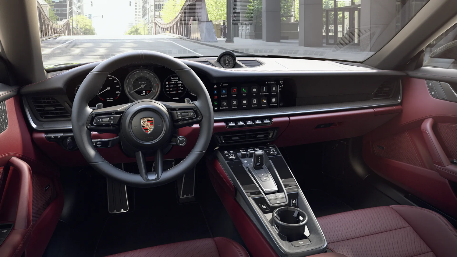 A Porsche 911 Turbo interior featuring burgundy leather seats and a sleek digital dashboard with touchscreen display.