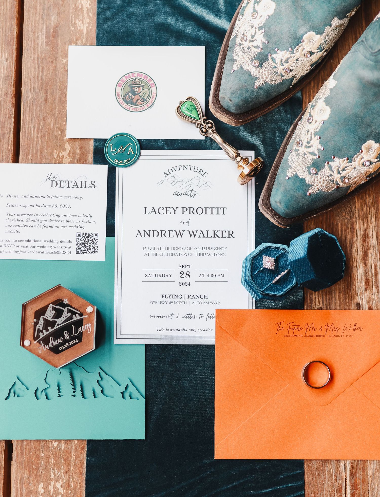 Wedding invitation suite with teal and orange details laid out on wooden surface.