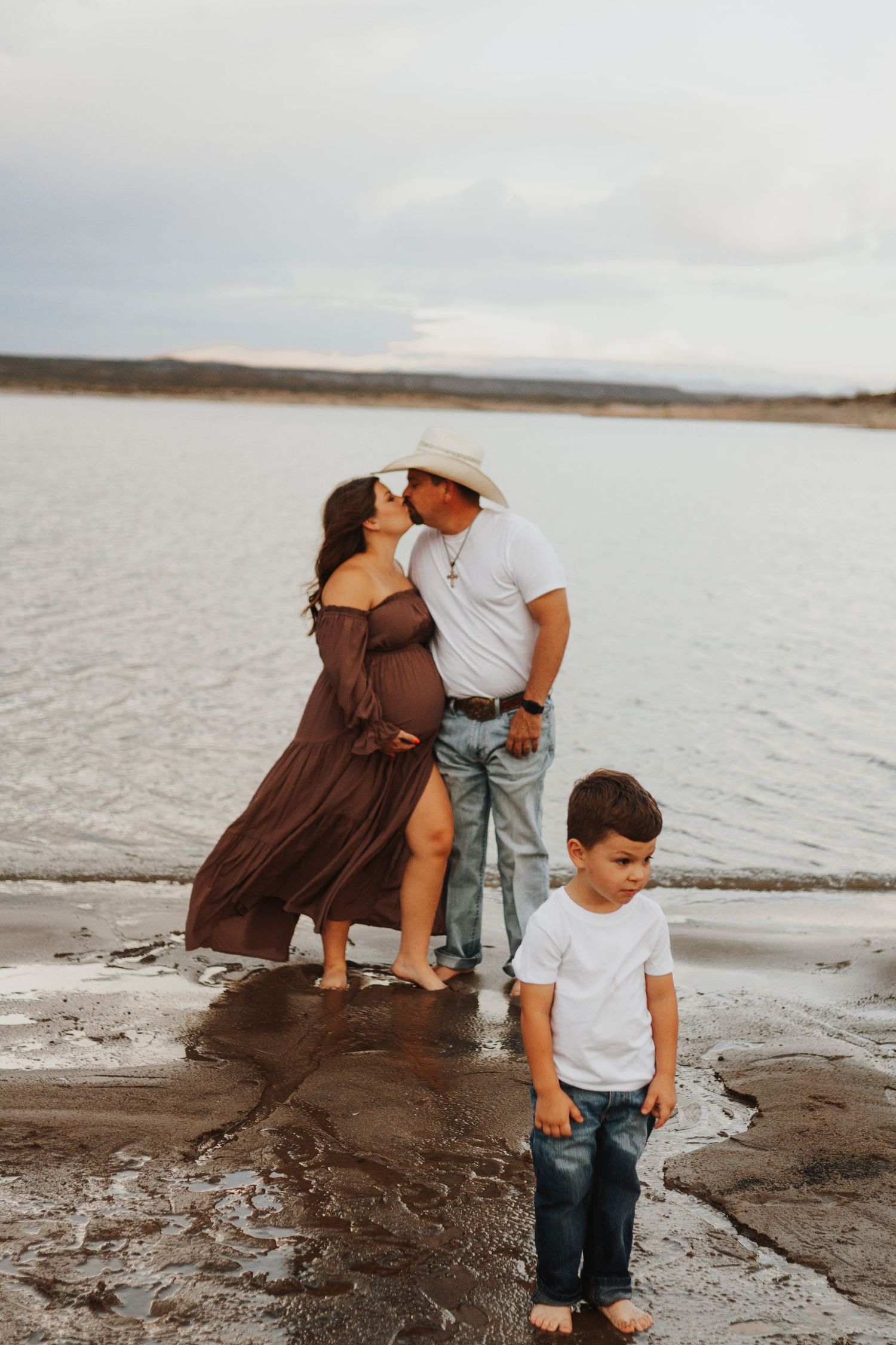 Family enjoying time together at shoreline of lake or beach during cloudy day.