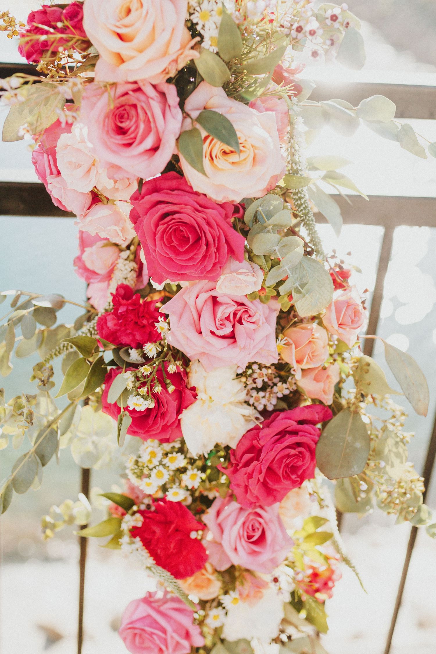 Beautiful cascading floral arrangement with pink and peach roses and greenery.