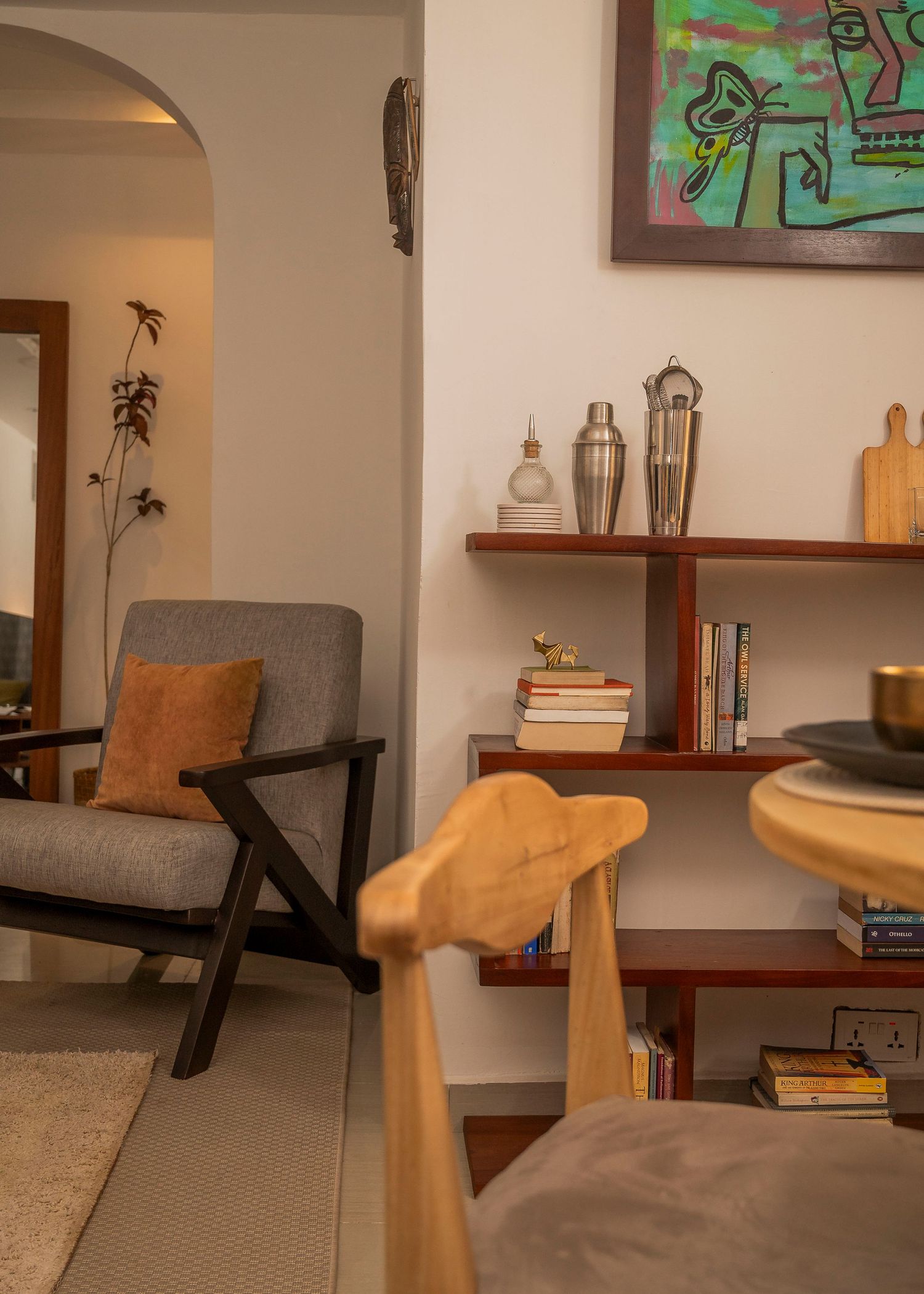 Living room interior with minimalist furniture and floating shelves displaying books and decor.