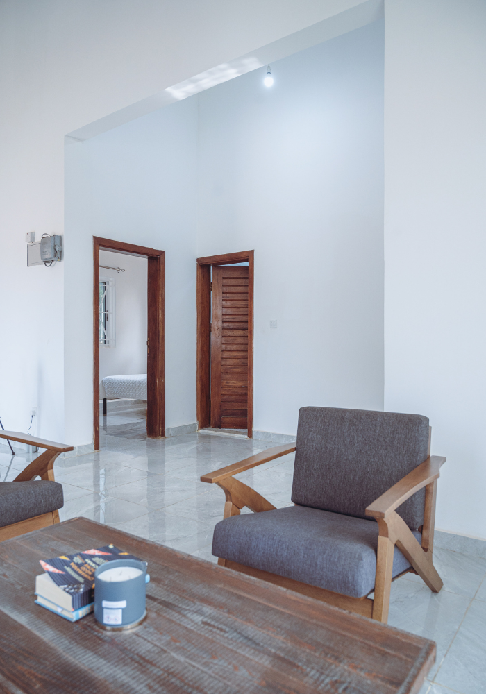 Modern living area with gray armchairs and wooden doors showcasing minimalist design.
