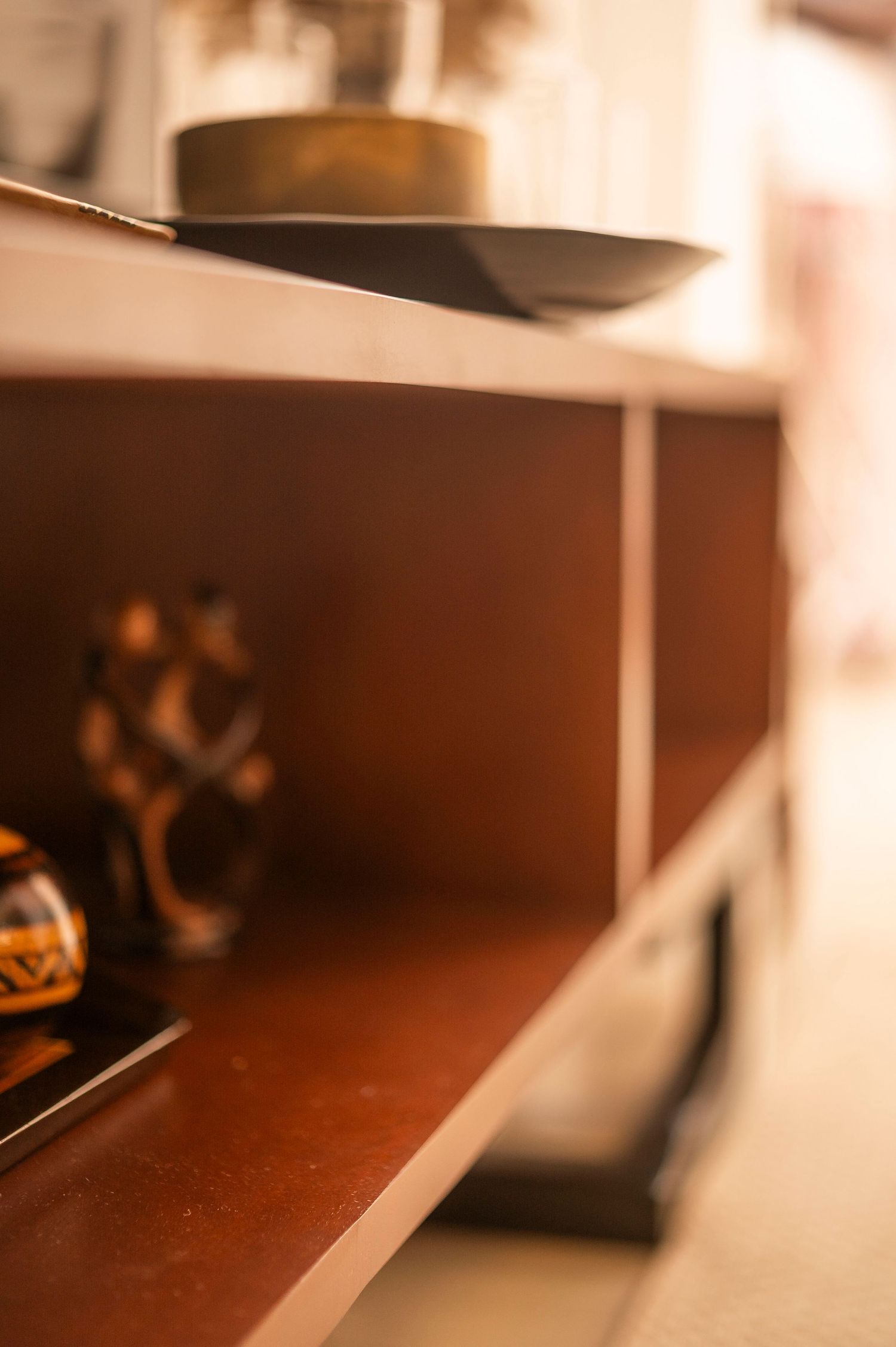 Angled shot of wooden furniture shelving with decorative objects in soft brown tones.