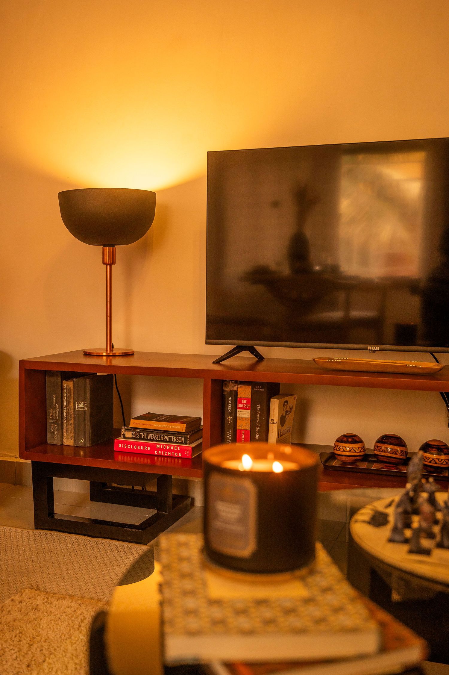 TV entertainment unit with copper lamp and black candle creating warm ambient lighting.