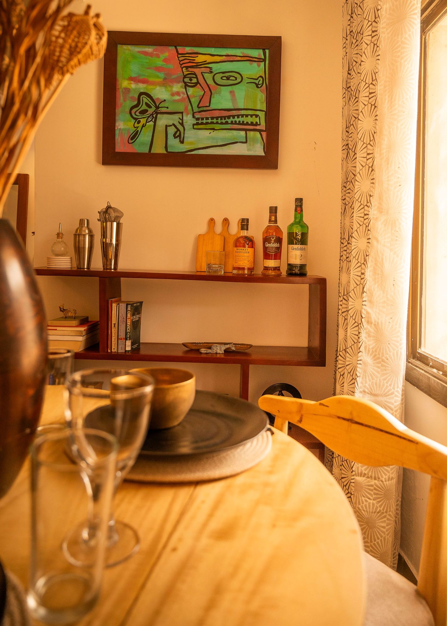 Contemporary living space with colorful wall art and a bar shelf displaying bottles.