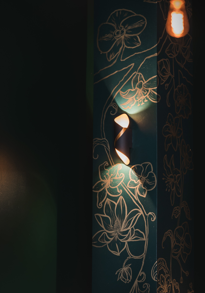 Elegant floral design illuminated on dark teal wall with decorative lighting.