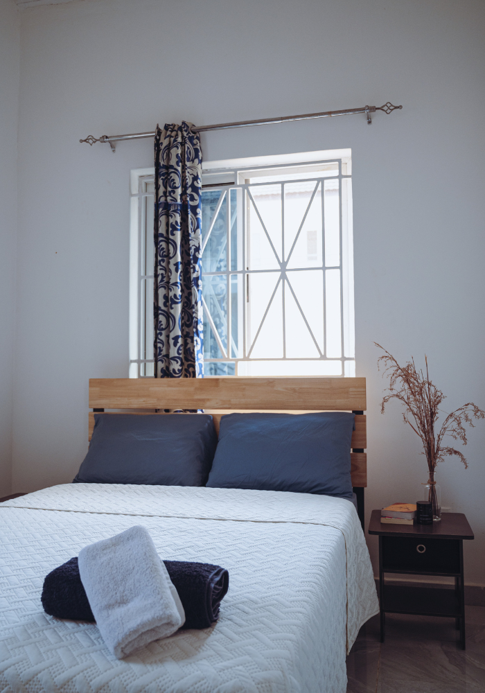 Contemporary bedroom with blue pillows, wooden headboard, and geometric window design.