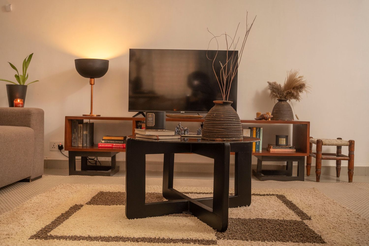 Low-angle view of modern living room with black coffee table, TV unit, and neutral decor.