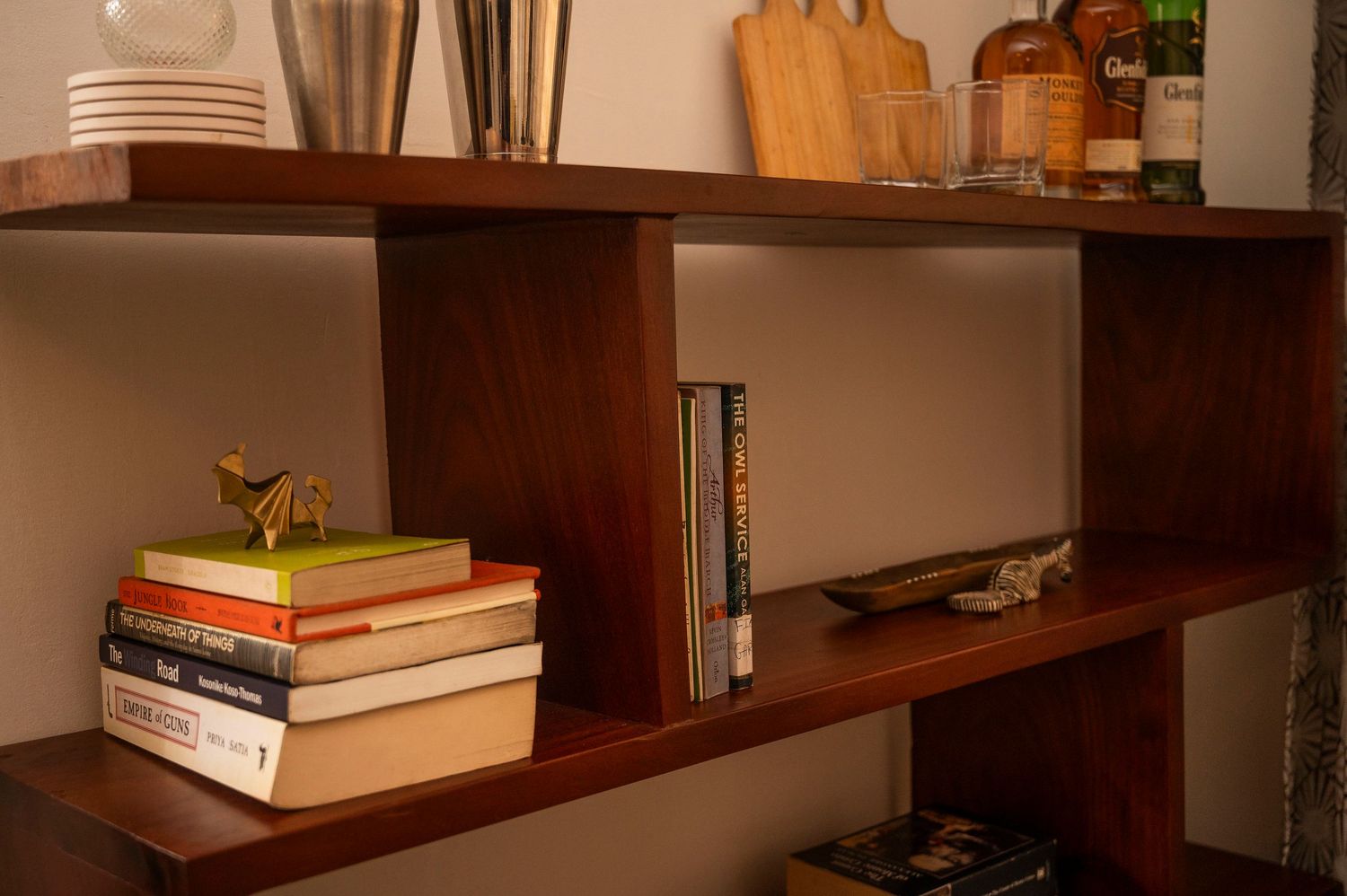 Wooden bookshelf with stacked books and skateboard displayed in minimalist style.