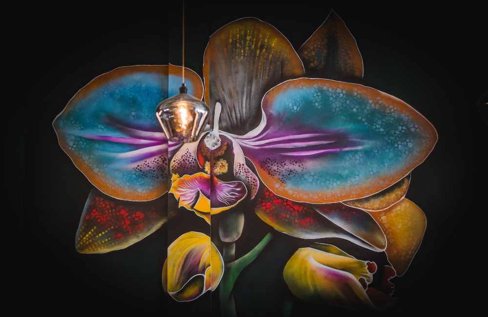 Vibrant artistic mural of a large orchid flower with turquoise petals against a dark background.
