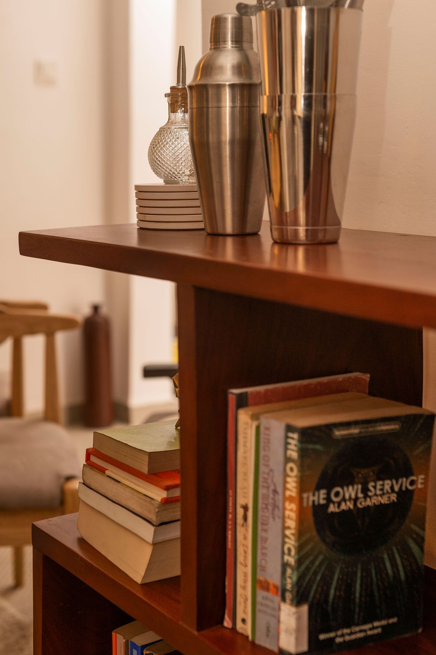 Wooden shelf displaying books and metallic decorative items in warm lighting.