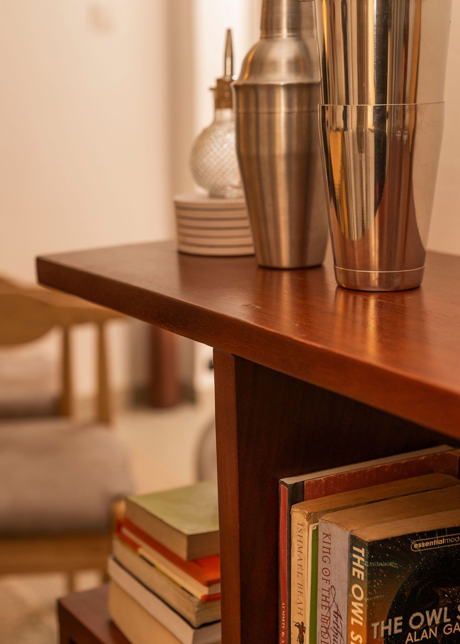 Cocktail mixing equipment and stainless steel shakers displayed on wooden shelving unit.