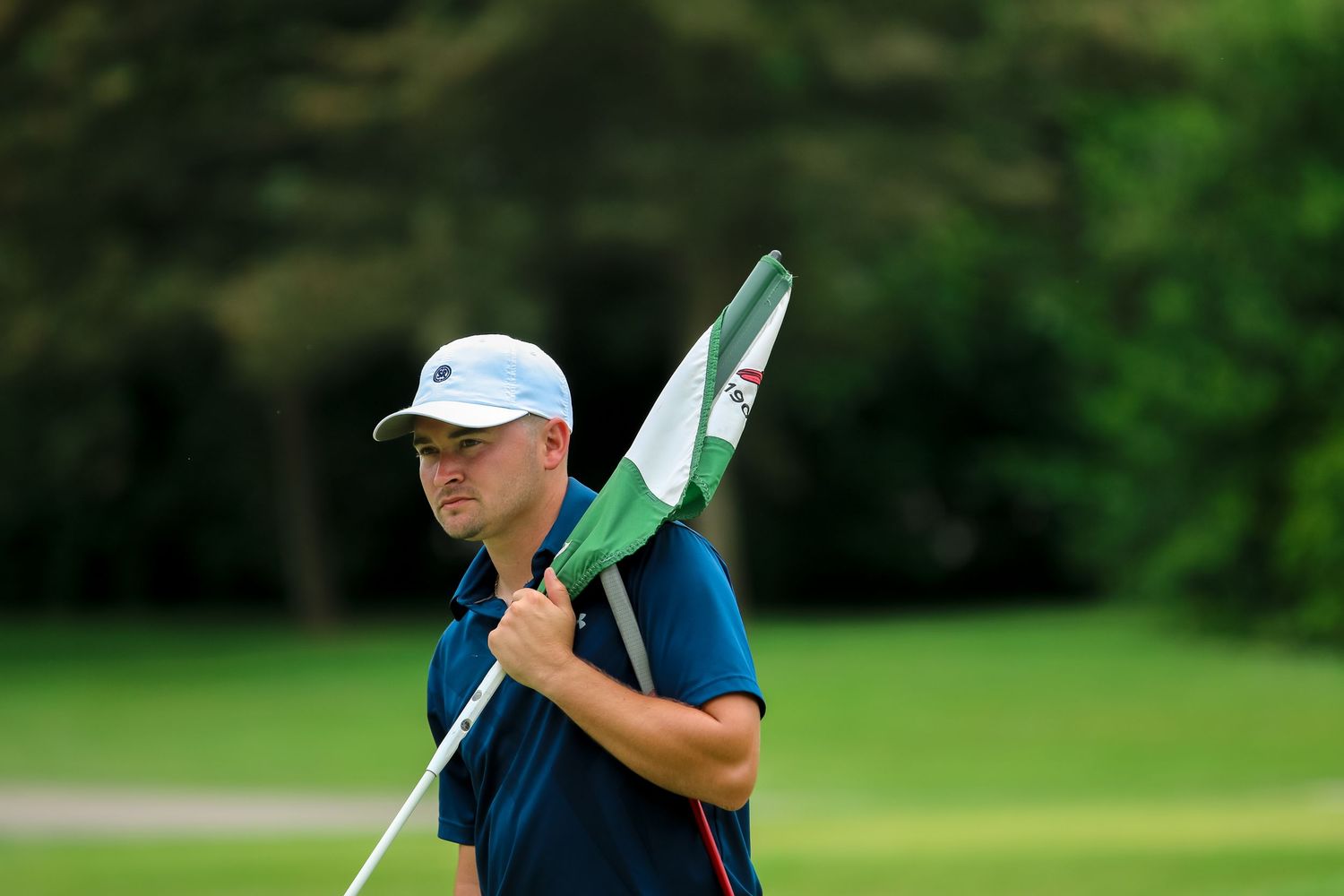 Golfer in a navy shirt holding the flag