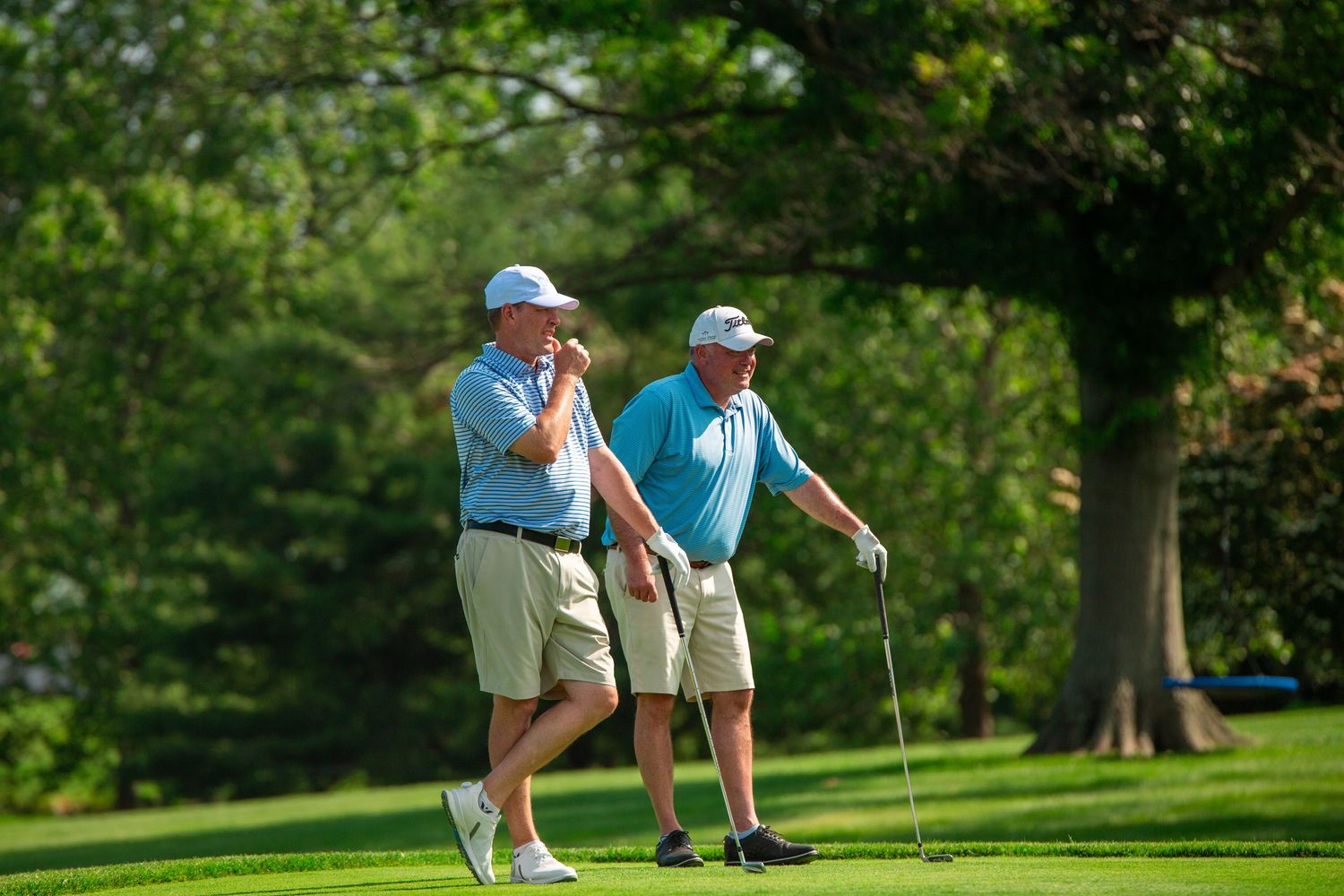 two golfers on a putting green reading a putt