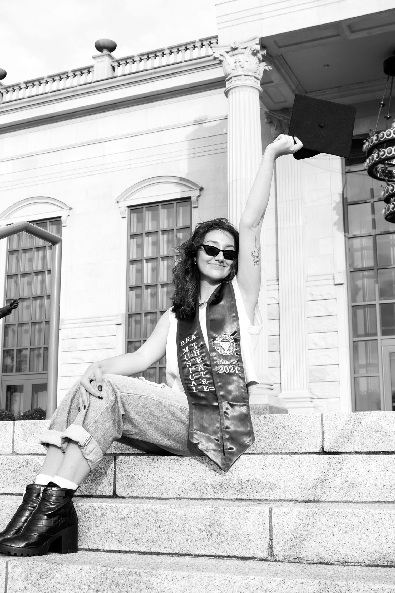 Black and white portrait series of person lounging on stone ledge by historic building.