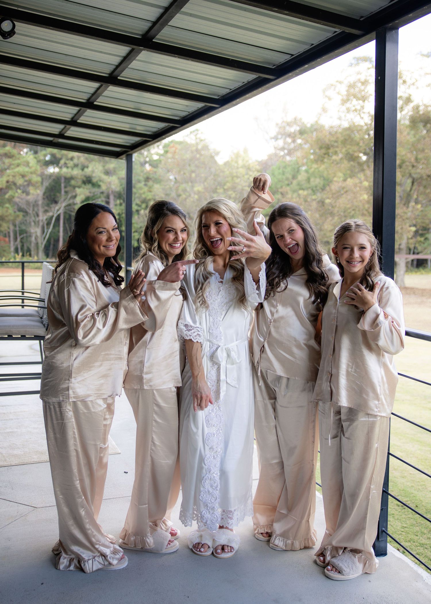 A group in matching beige outfits poses playfully together under a covered outdoor area.